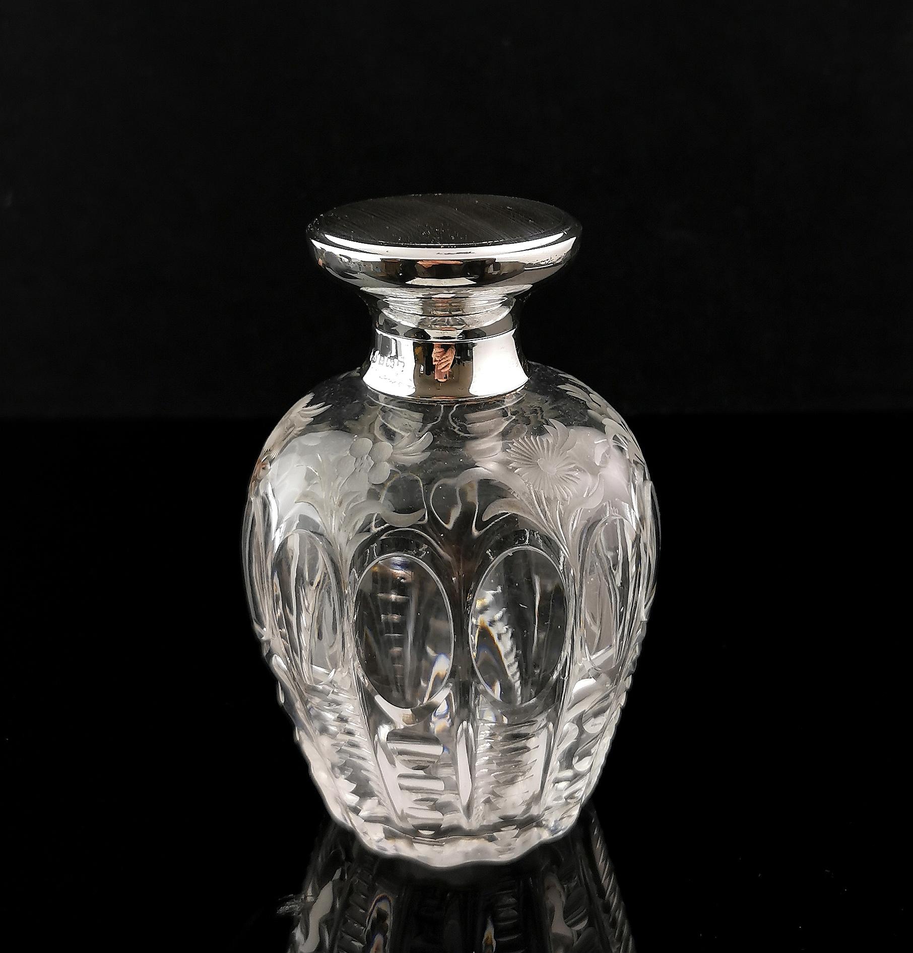 A truly stunning antique Art Deco era scent bottle.

It is a large ovoid shaped bottle with lobed sides and with a delicate, pretty floral design etched into the top sections of the body.

The lid is made from sterling silver with an engine turned