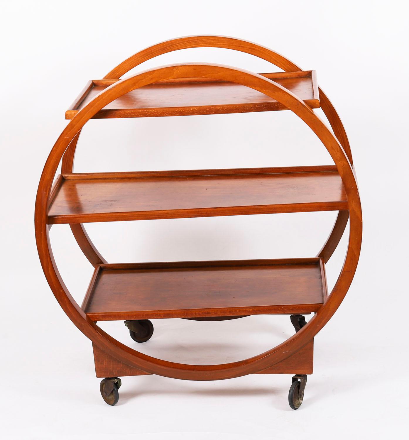 Se trata de un llamativo carrito de azafata antiguo Art Decó de tres pisos de nogal figurado que data de la década de 1920.

El carro tiene forma circular decorativa y está equipado con ruedas.

Se trata de un carro de servicio muy divertido que