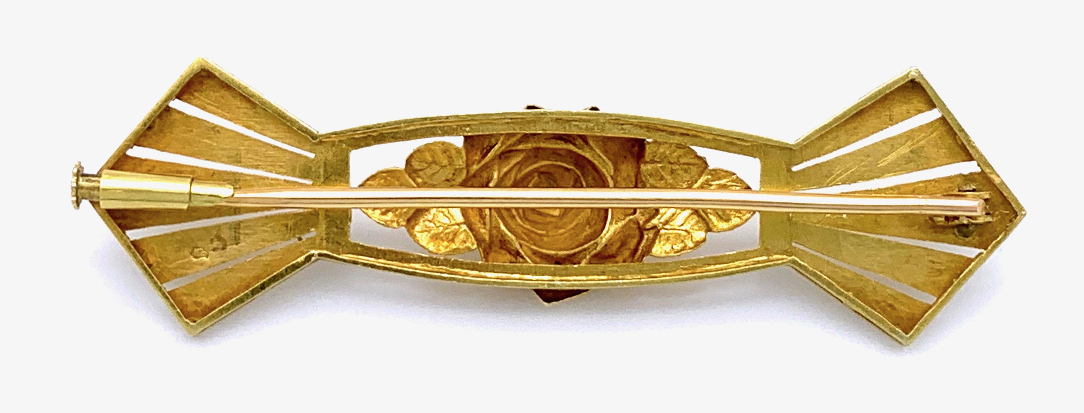 This charming Art Deco brooch is designed as a rose in full bloom surrounded by leaves and a partially enamelled frame with stilized sunbeams.
On the reverse are French goldmarks for 18k and a serial number.