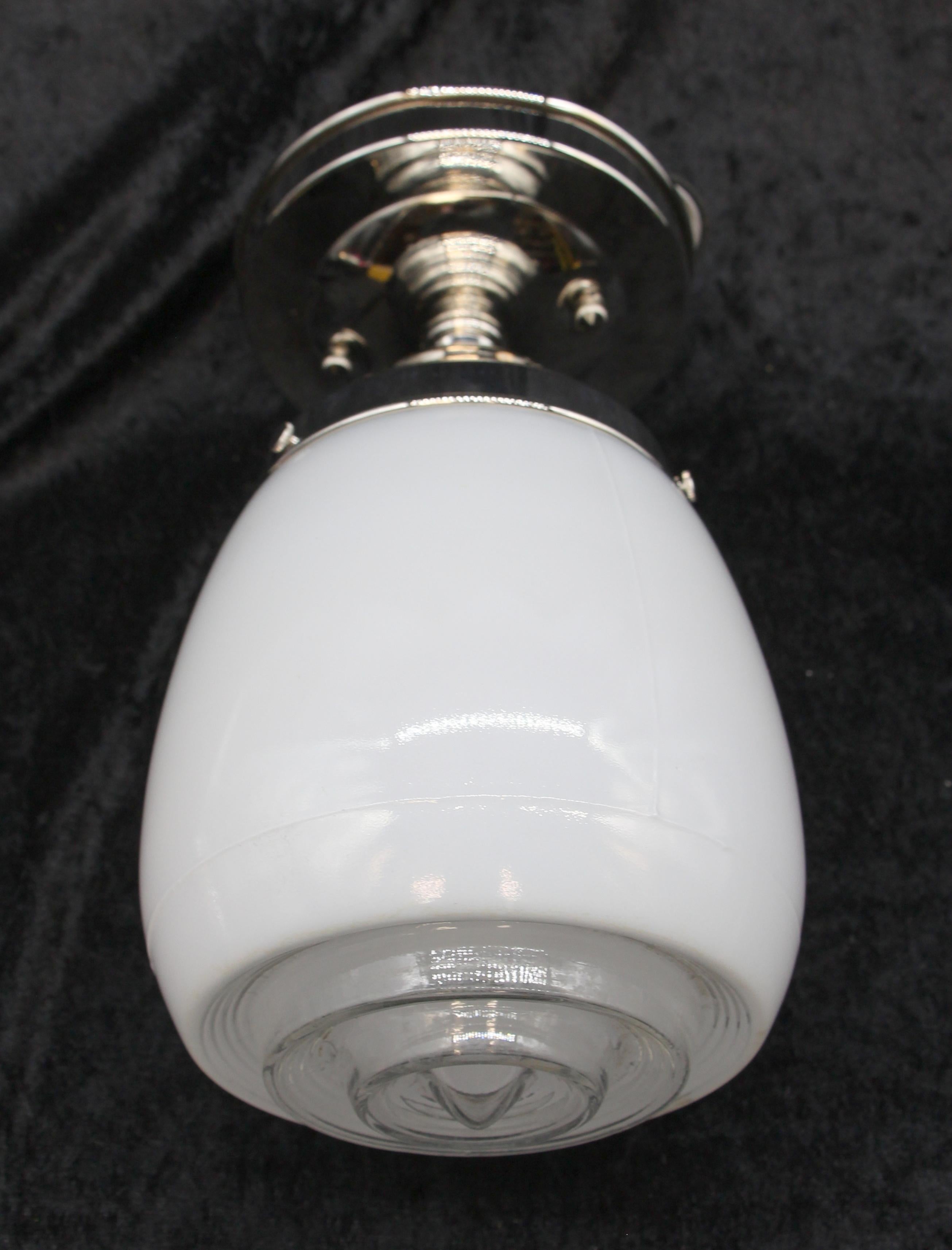 White glass Art Deco style shade mated to a semi flush mount light fixture with a nickel finish This shade features a clear concentric glass bottom to direct light downward.