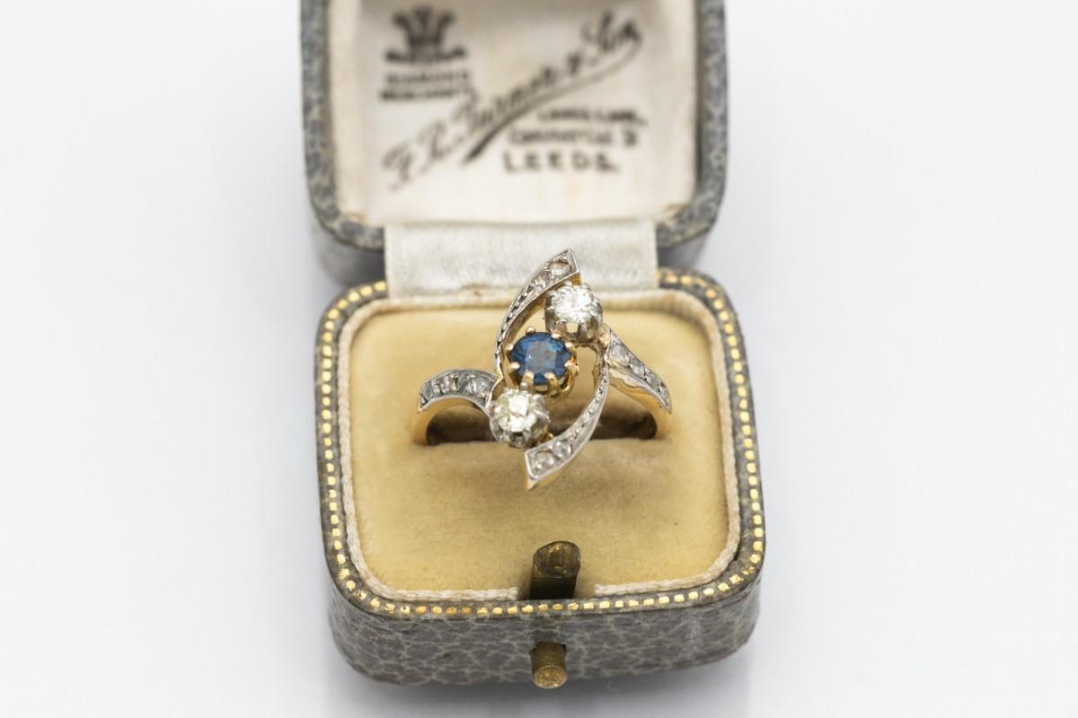 Impressionnante bague ancienne en or jaune 18 carats avec des éléments en platine. Serti d'un saphir central facetté de couleur bleu clair pesant 0,60ct. En outre, deux diamants en taille brillant ancienne d'un poids total d'environ 0,35ct. Forme