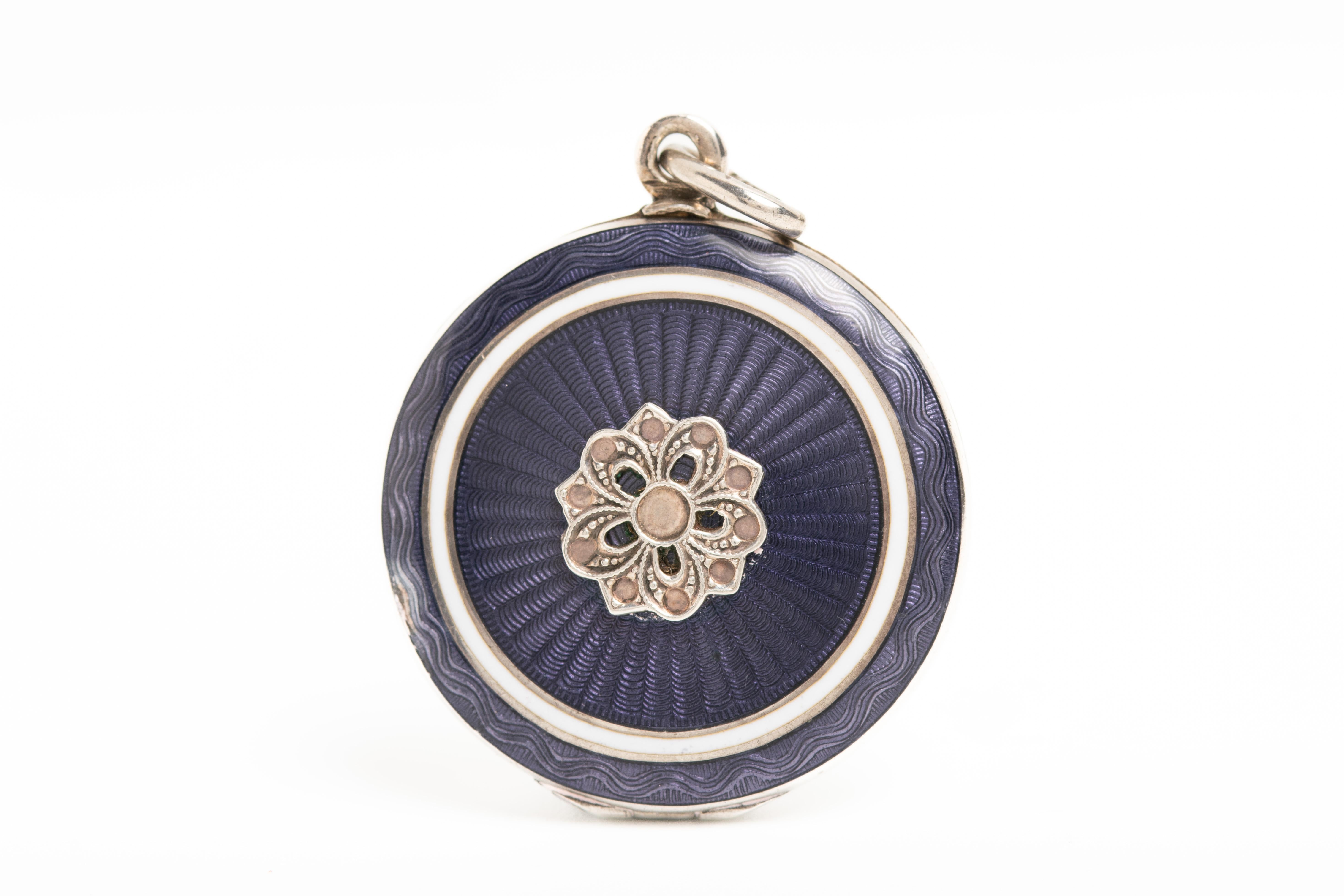This antique purple guilloche enamel and silver locket comes from Austria and its beautifully decorated with a floral silver motif in the centre. The locket opens to reveal two compartments for the photographs. This Art Deco beauty is hallmarked 935