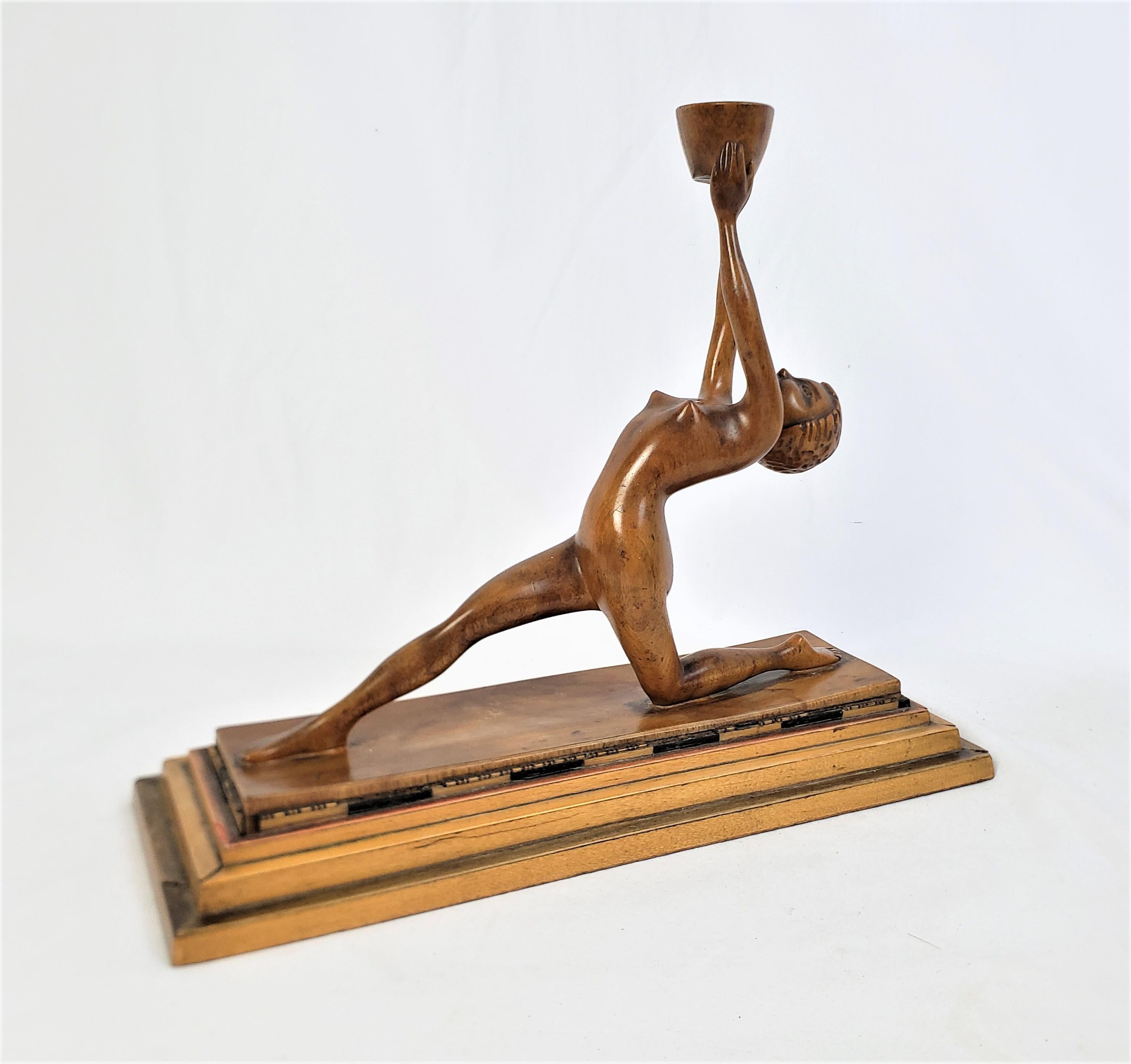 This hand-carved Art Deco sculpture is unsigned, but presumed to have originated from France and date to approximately 1920 and done in the period Art Deco style. The sculpture is done in a softwood and depicts a stylized recling nude female holding