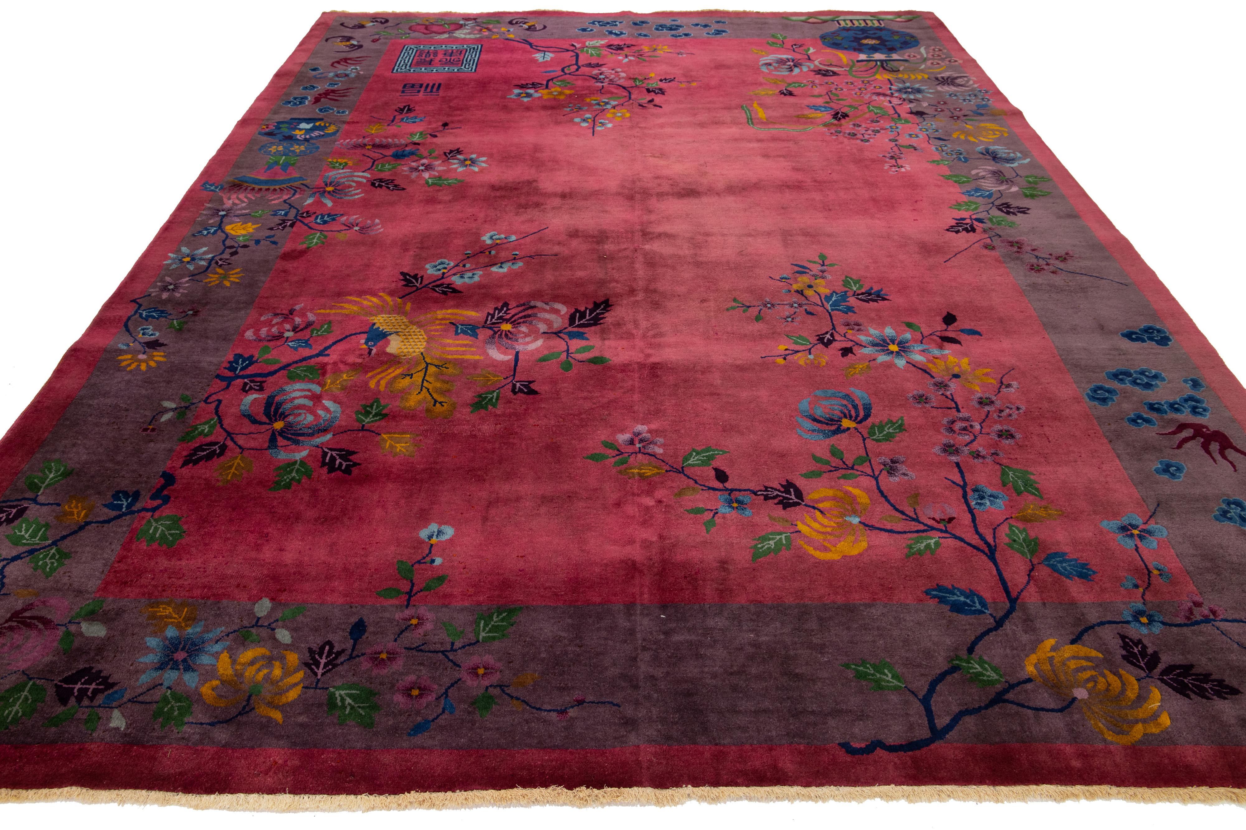 Ce superbe tapis chinois antique de style Art déco est noué à la main de manière experte à partir de laine de première qualité. Il présente un riche fond rouge bordeaux orné d'un vibrant motif floral multicolore, élégamment encadré par une bordure