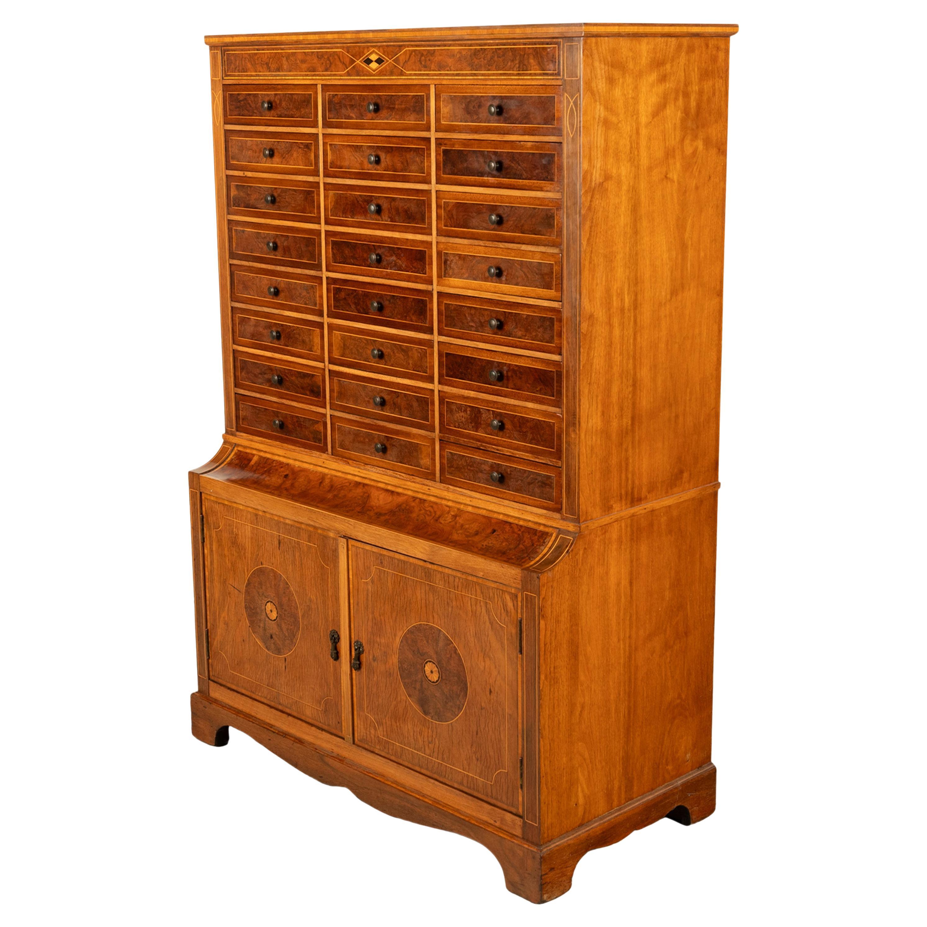 Un beau et rare meuble de collection ou classeur à 24 tiroirs en noyer et marqueterie de l'Art Déco américain, vers 1920.
Le meuble est fabriqué en très beau noyer figuré et ronce, le dessus du meuble étant incrusté de lignes de buis avec un