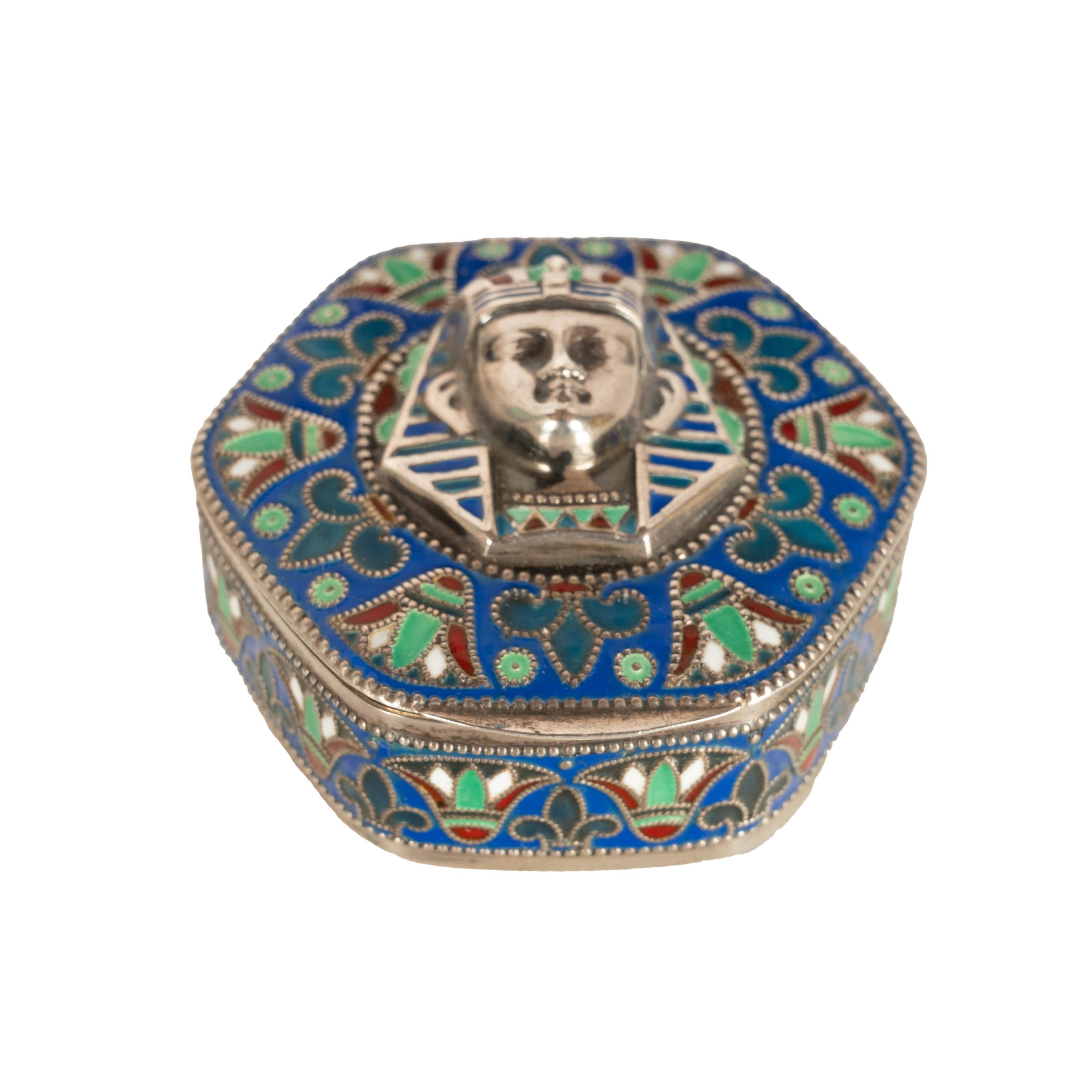 Antike ägyptische Revival Art Deco emailliert 800 Grad Silber vergoldet Cloisonne-Emaille-Box, Italien, um 1925.
Die sechseckige Dose mit Scharnierdeckel ist mit dem Kopf eines Pharaos/Königs Tutanchamun verziert, der in tiefem Relief auf blauem