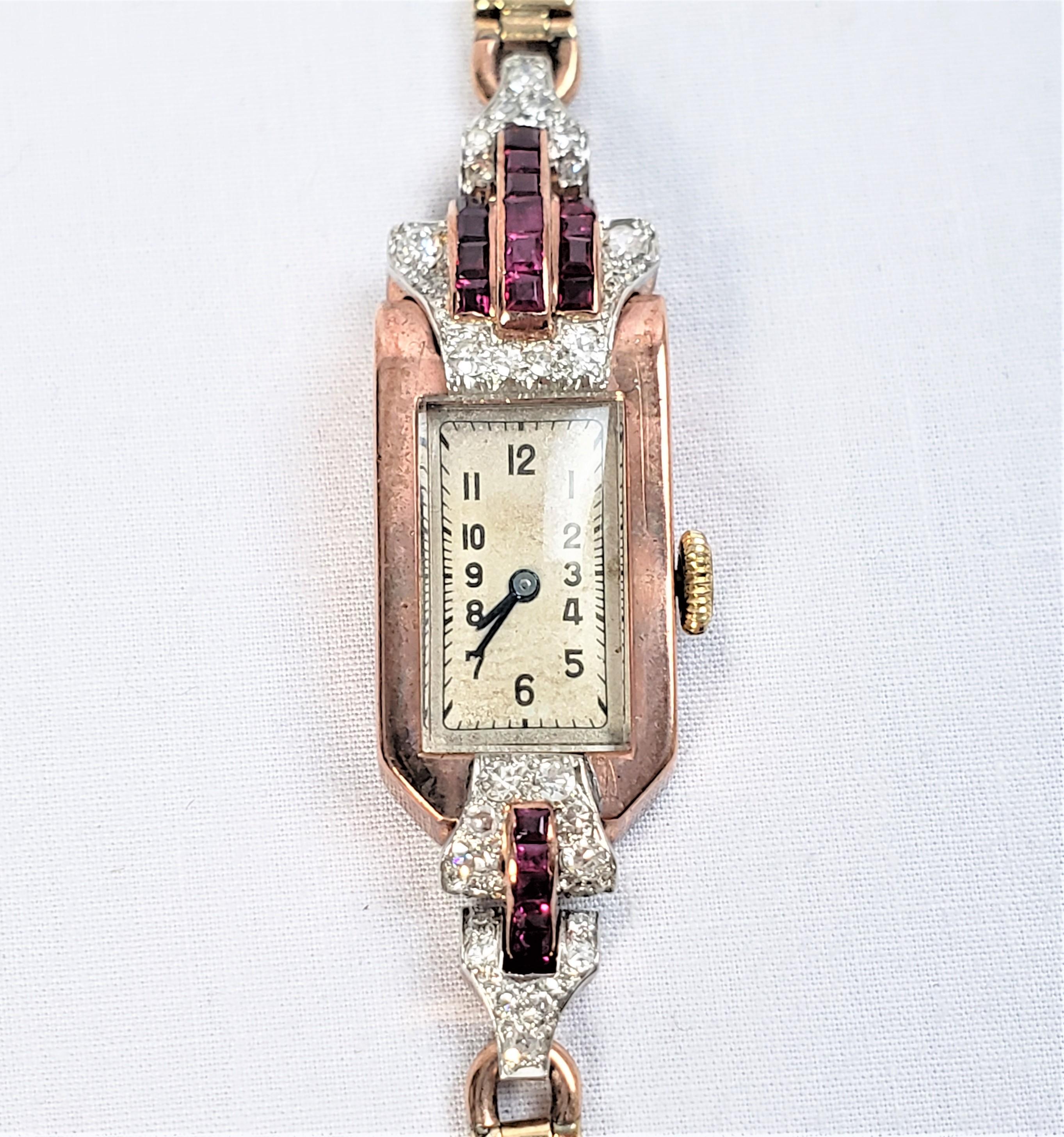 This antique ladies cocktail or evening watch is hallmarked as originating from England and dates to approximately 1920 and done in the period Art Deco style. The case and band are composed of 9 karat rose gold with diamond and synthetic ruby