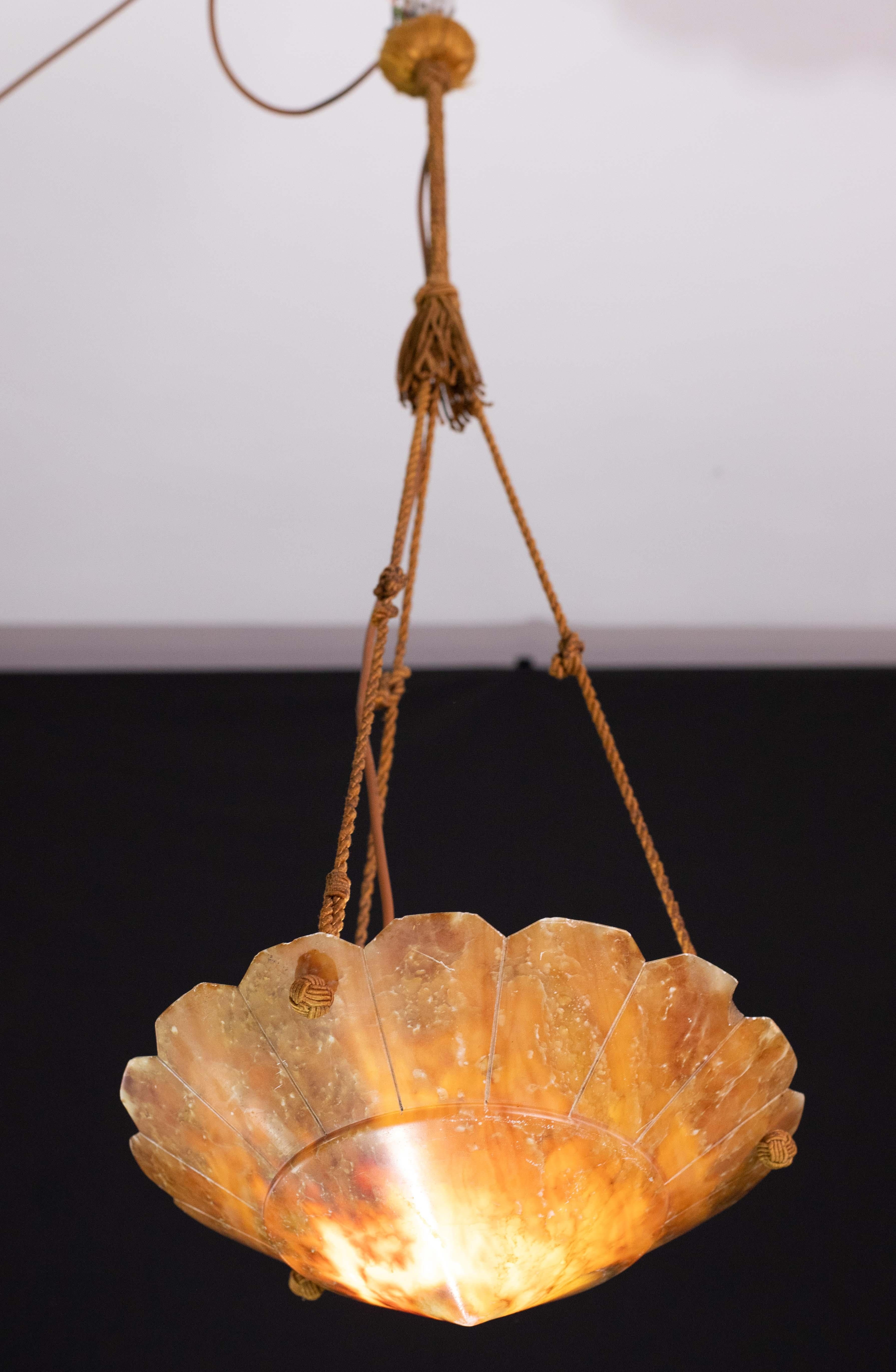 Antique Art Deco style alabaster pendant light, circa 1940s.
A unique piece in alabaster, beautifully worked with shades and reflections of other colors when illuminated, suspended by three cords (threads).
The light that shines through the