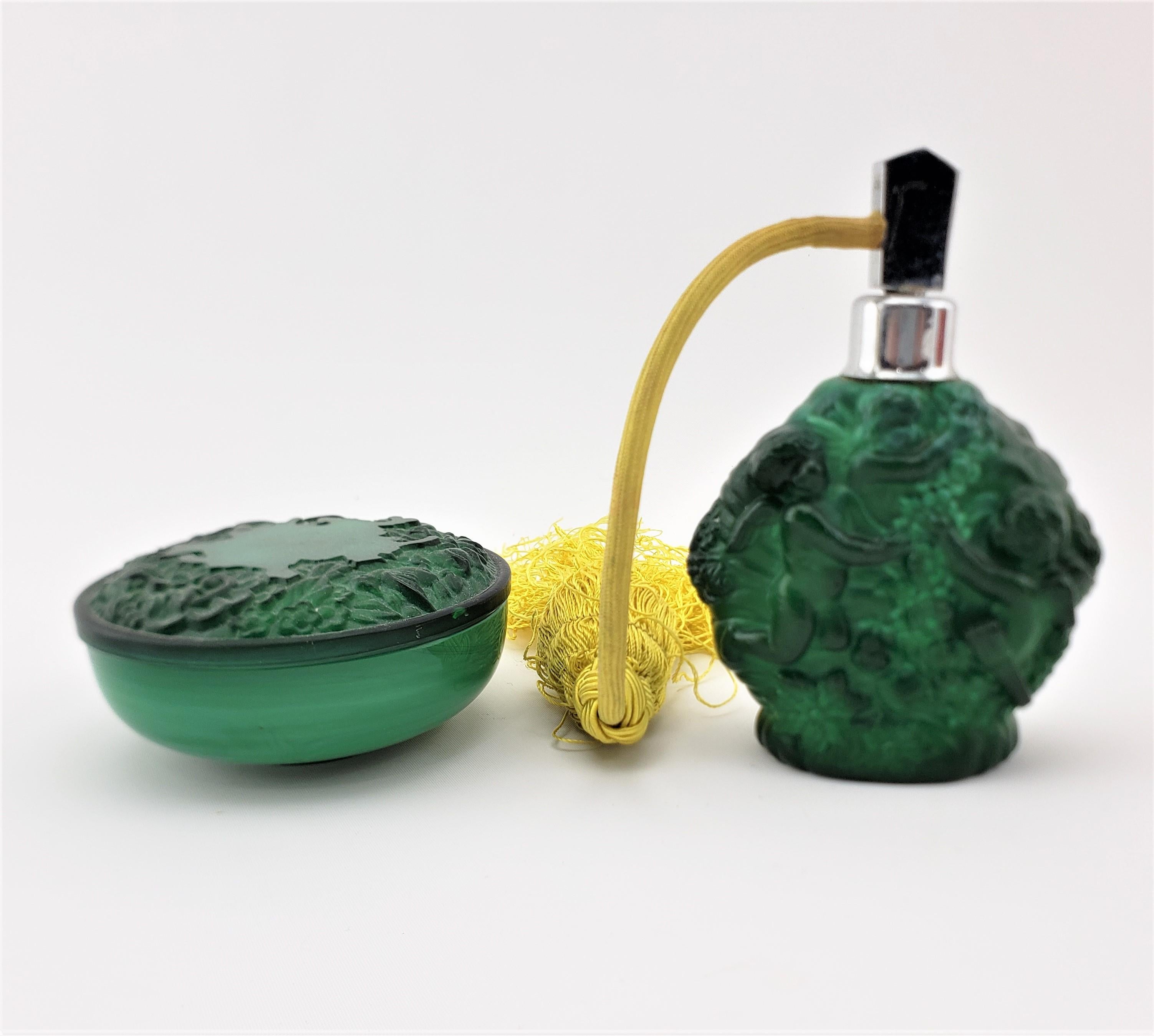 This antique dresser jar and perfume bottle are unsigned, but presumed to have been made in Austria in approximately 1920 in the period Art Deco style. The set is done in deep green malachite colored glass and is decorated with neoclassical figures