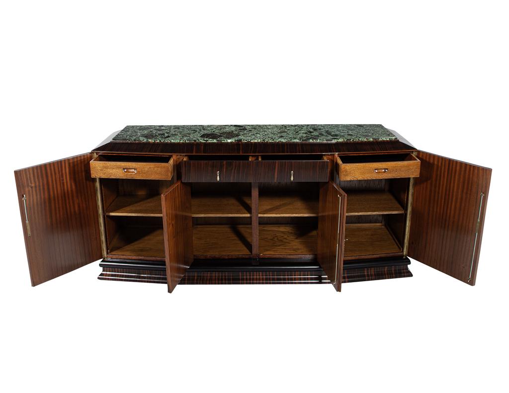 Questo squisito mobile da buffet in stile Art Déco, proveniente dalla Francia di Nantes intorno agli anni '30, unisce perfettamente eleganza e funzionalità. Il piano in marmo verde è un elemento centrale di grande effetto, completato dalle calde