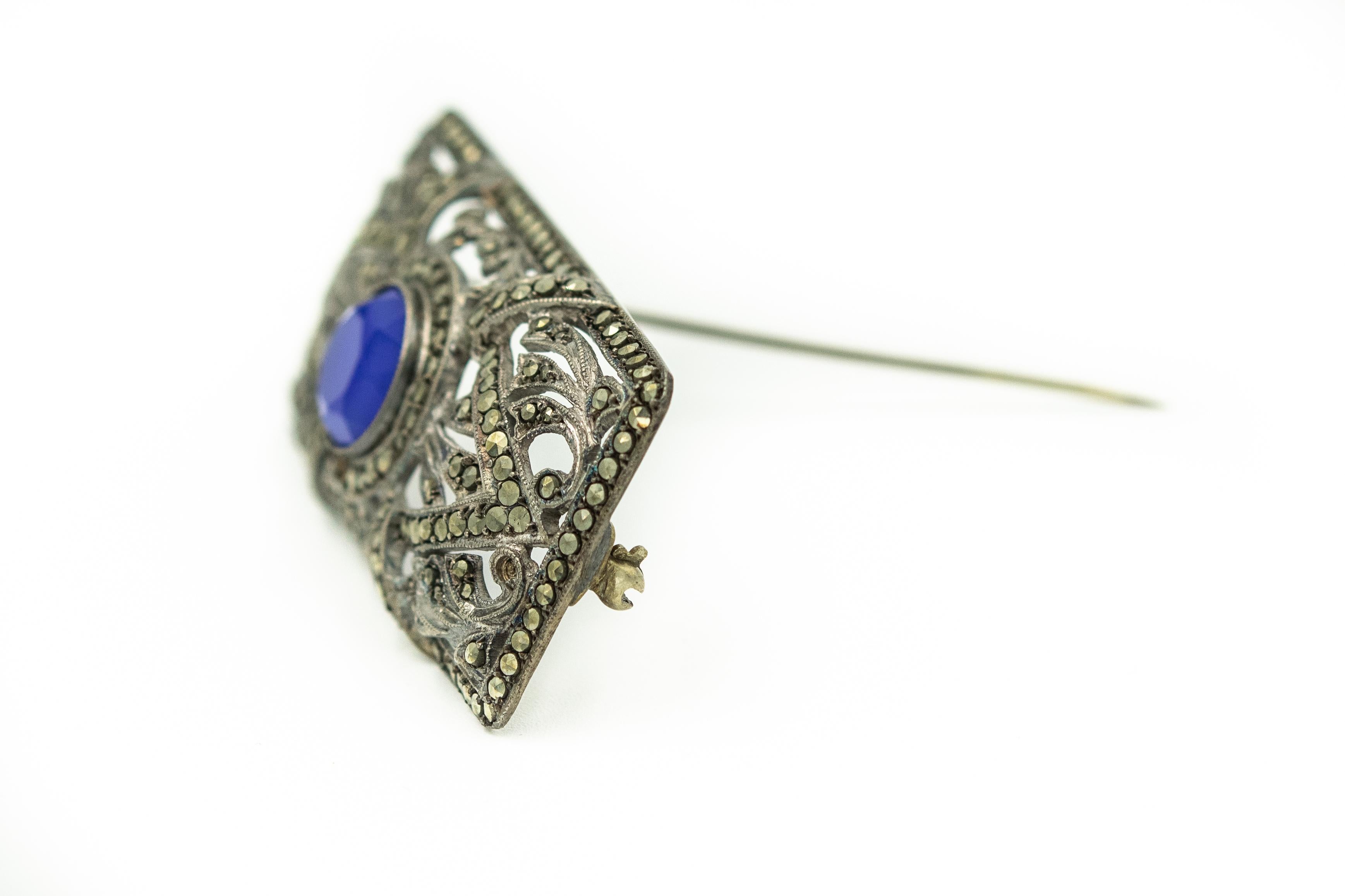 Art Deco rectangular brooch featuring a filagree openwork design with a blue glass stone in the center.  

It is marked 935 silver probably German (normal sterling silver is 925 so this is a higher purity)