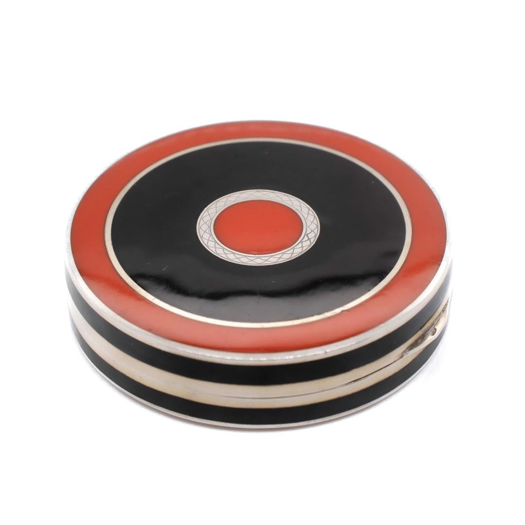 Eine feine Art Deco Zeit kompakt.

Von Meyle & Meyer.

Aus .935er Sterlingsilber.

Verziert auf der Oberseite und der Basis in einem passenden Bullseye-Muster, bestehend aus konzentrischen Ringen aus Sterlingsilber und schwarzer und roter Emaille,