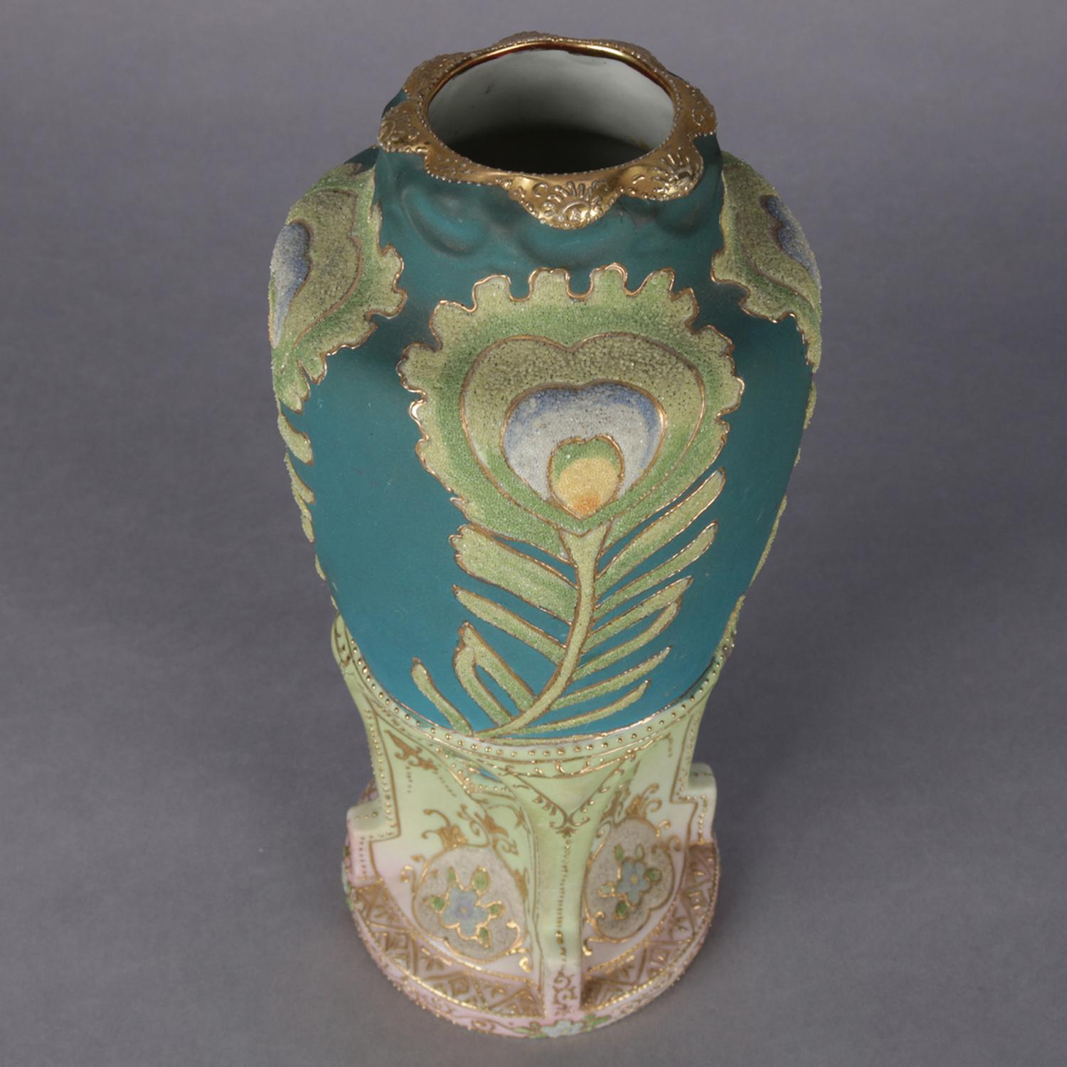 An antique Japanese Art Deco Nippon Coraline decorated vase features double handled urn form with ruffled gilt rim, all-over moriage decorated with stylized peacock feathers, buttress form base and heavy gilt beading and highlights, marked on base,