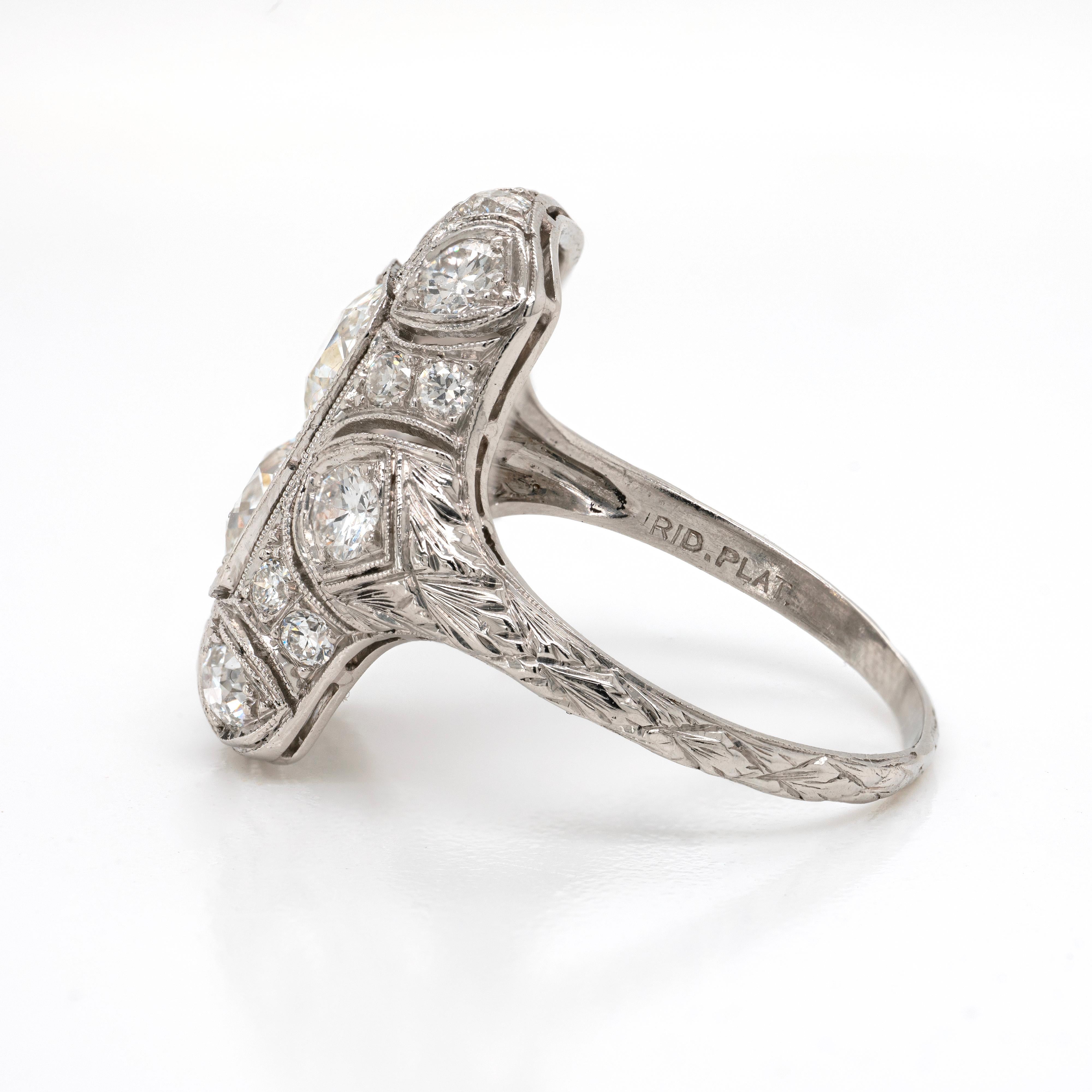 This antique platinum dress ring is typical of the Art Deco period with its spectacular design. The ring features centrally two old mine cut diamonds in a rectangular, open back, milgrain edged setting. The piece is further decorated with 16 old