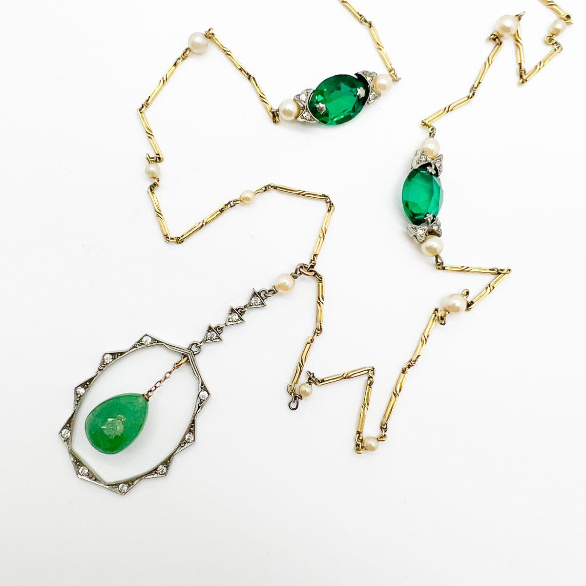 A sublime Antique Art Deco Pearl Lariat dating to the 1920s and the flapper era. A fancy bar link chain embellished with pearls sets the scene. Emerald paste adorns the chain in white settings in step with the white metal pendant within which a