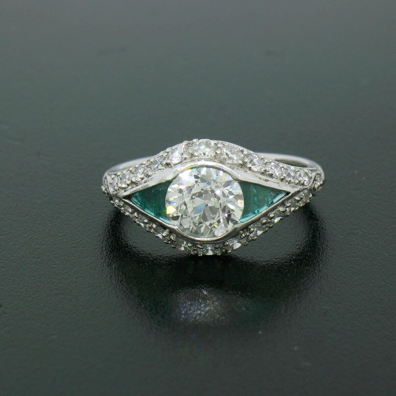 Here we have a very unique diamond and emerald engagement ring crafted in solid .900 platinum during the art deco period. It features a beautiful, VERY FINE QUALITY, old European cut diamond channel set at its center. The diamond has colorless E