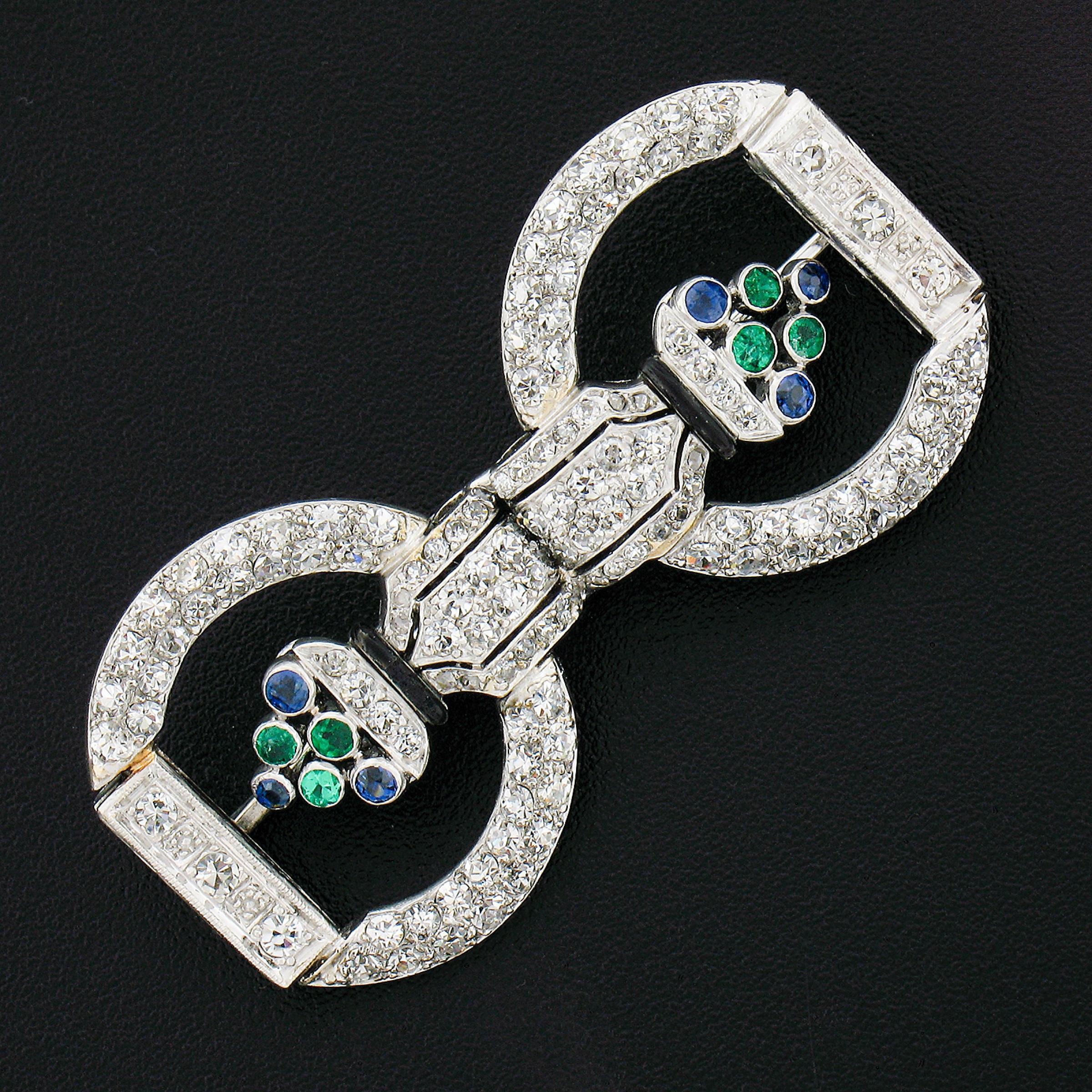 This stunning antique pin/brooch is crafted in solid platinum during the art deco period. It features the most adorable floral patterns and is completely drenched with fine quality old European and single cut diamonds, six genuine emeralds and six