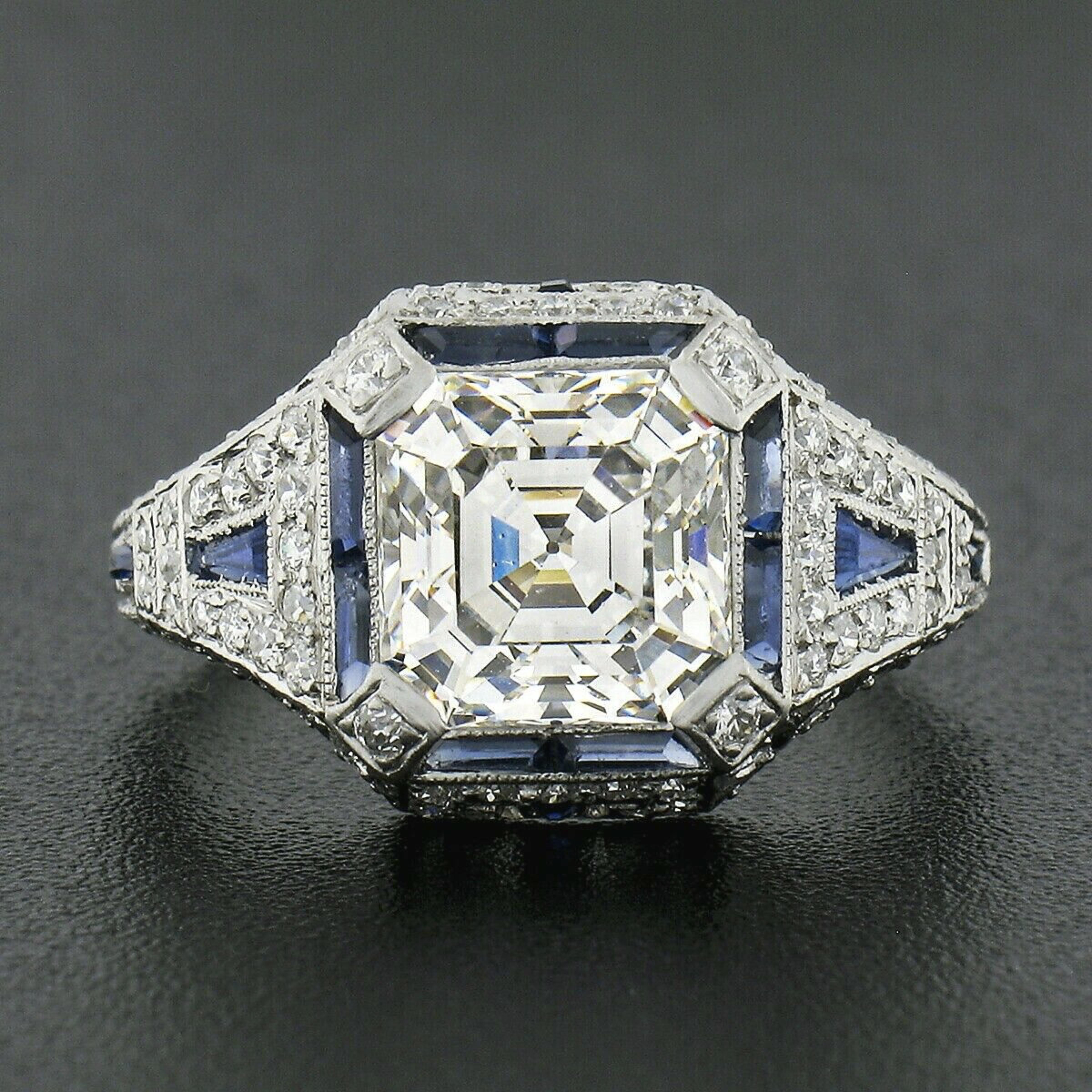 Here we have an absolutely breathtaking antique engagement ring that was crafted from solid platinum during the art deco period. This ring features a stunning, GIA certified, asscher cut (square emerald cut) diamond neatly prong set at the center of