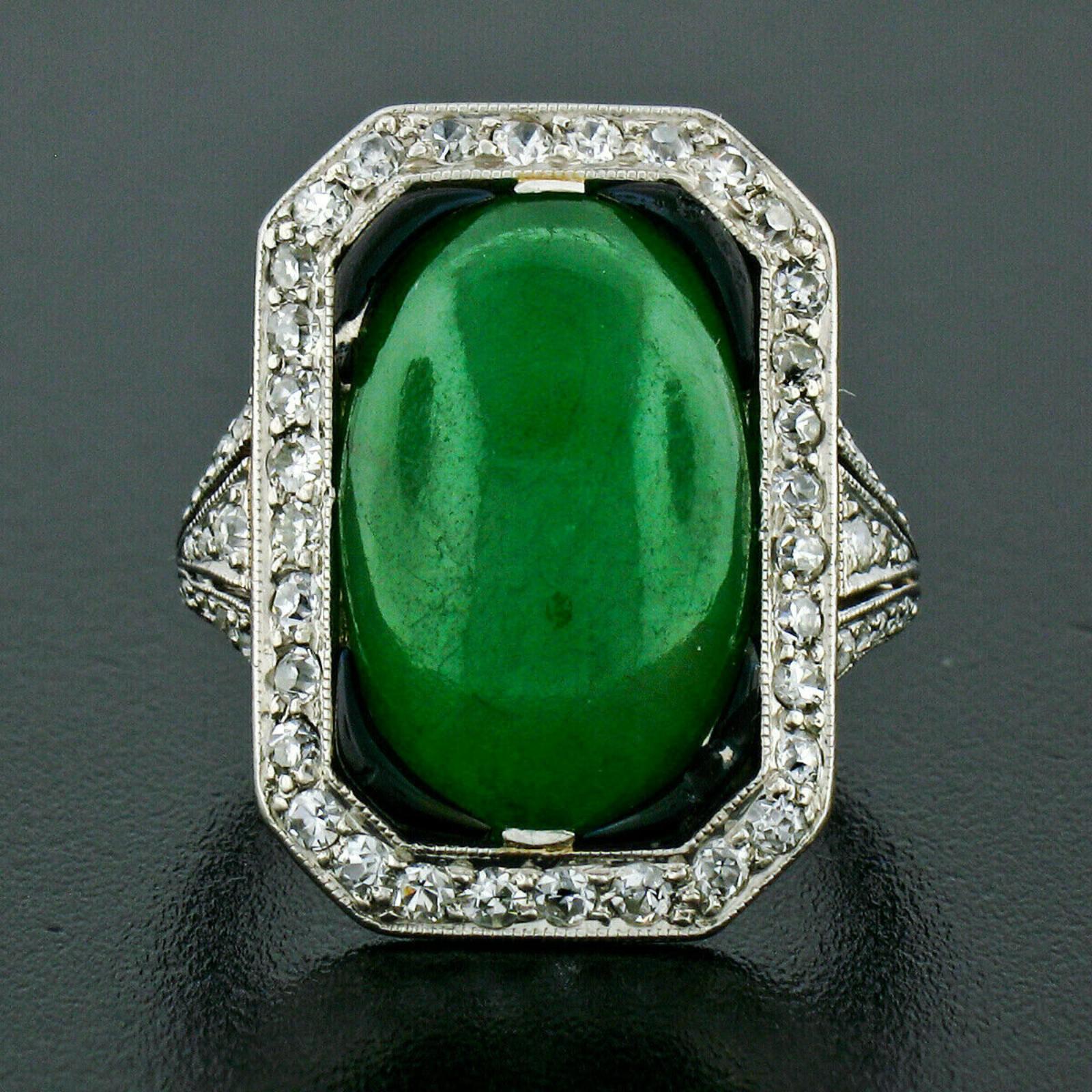 This truly unique and stunning antique art deco period cocktail ring crafted in solid platinum and features a breathtaking, GIA certified, natural jade stone that displays very rich and desirable green color over its oval cabochon shape. The stone