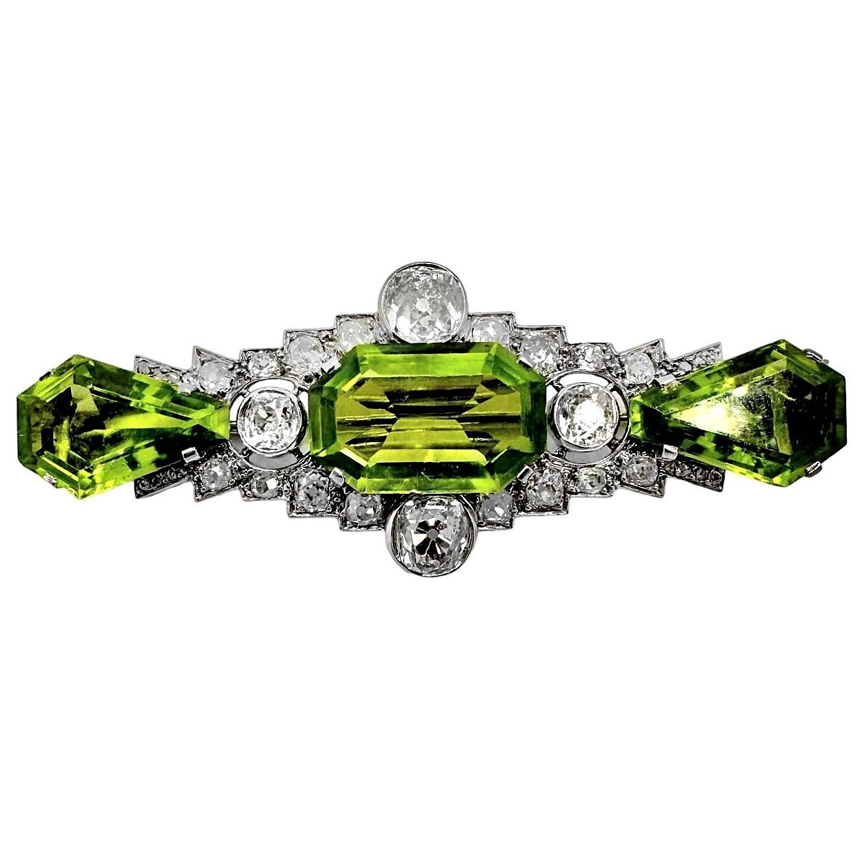 A spectacular early twentieth century brooch centered around an emerald cut peridot, surrounded by diamonds, and finished on either side with shield cut peridot. The central stone weighs approximately 10.5ct, and the combined weight of the two