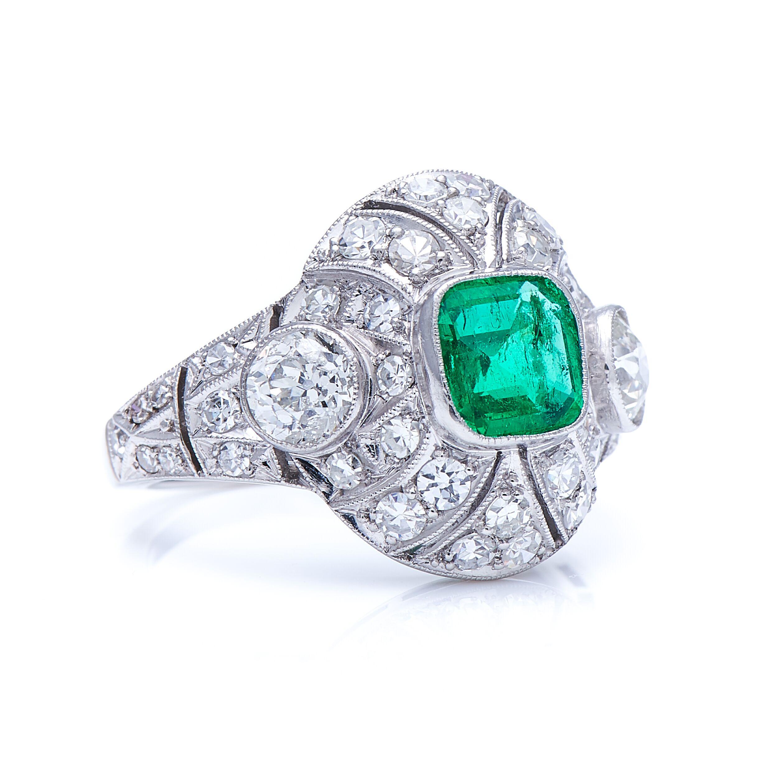 Emerald and diamond ring, circa 1925. The domed setting of this ring is hand pierced and set throughout with a variety of early circular-cut diamonds, and centres on a 0.9 carat step-cut Colombian emerald of a lush green hue, with excellent clarity,