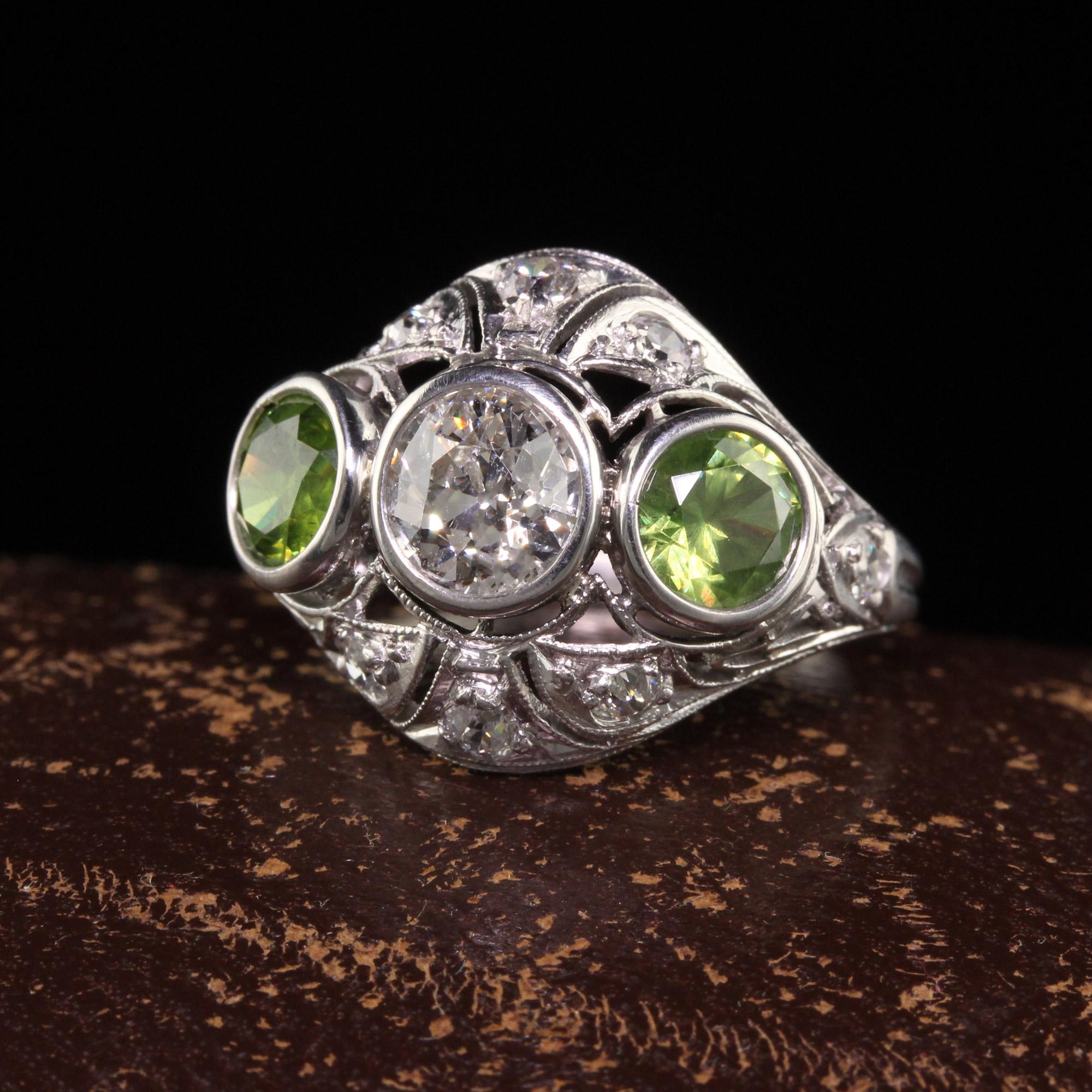 Beautiful Antique Art Deco Platinum Demantoid Garnet and Diamond Three Stone Ring. This incredible three stone ring is crafted in platinum. The ring holds two natural demantoid garnets with beautiful horsetail inclusions and an old mine diamond in