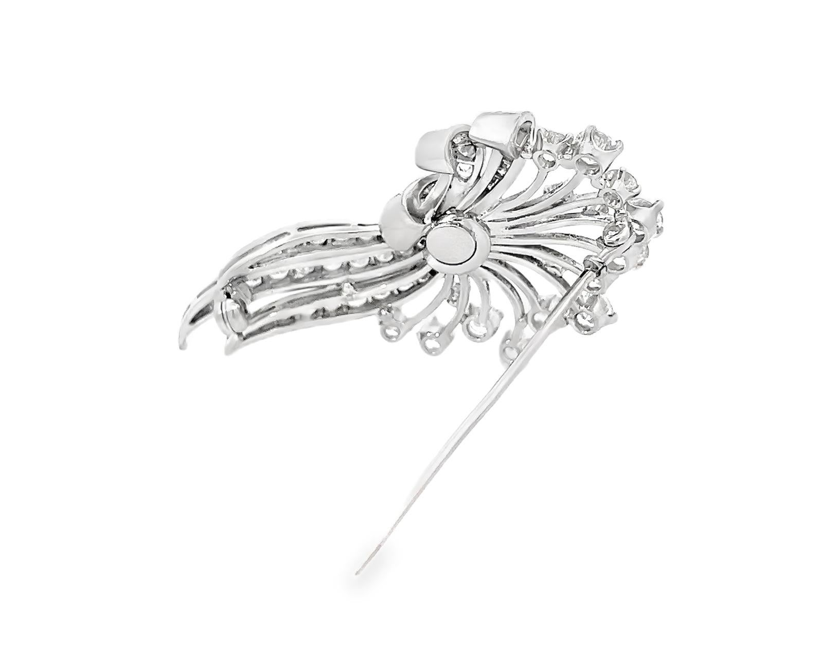 The Art Deco platinum diamond brooch showcases a dazzling arrangement of round and baguette cut diamonds in an intricate floral fan design. Crafted in solid platinum (15.5 grams), this vintage antique brooch measures 5 cm x 3 cm and features