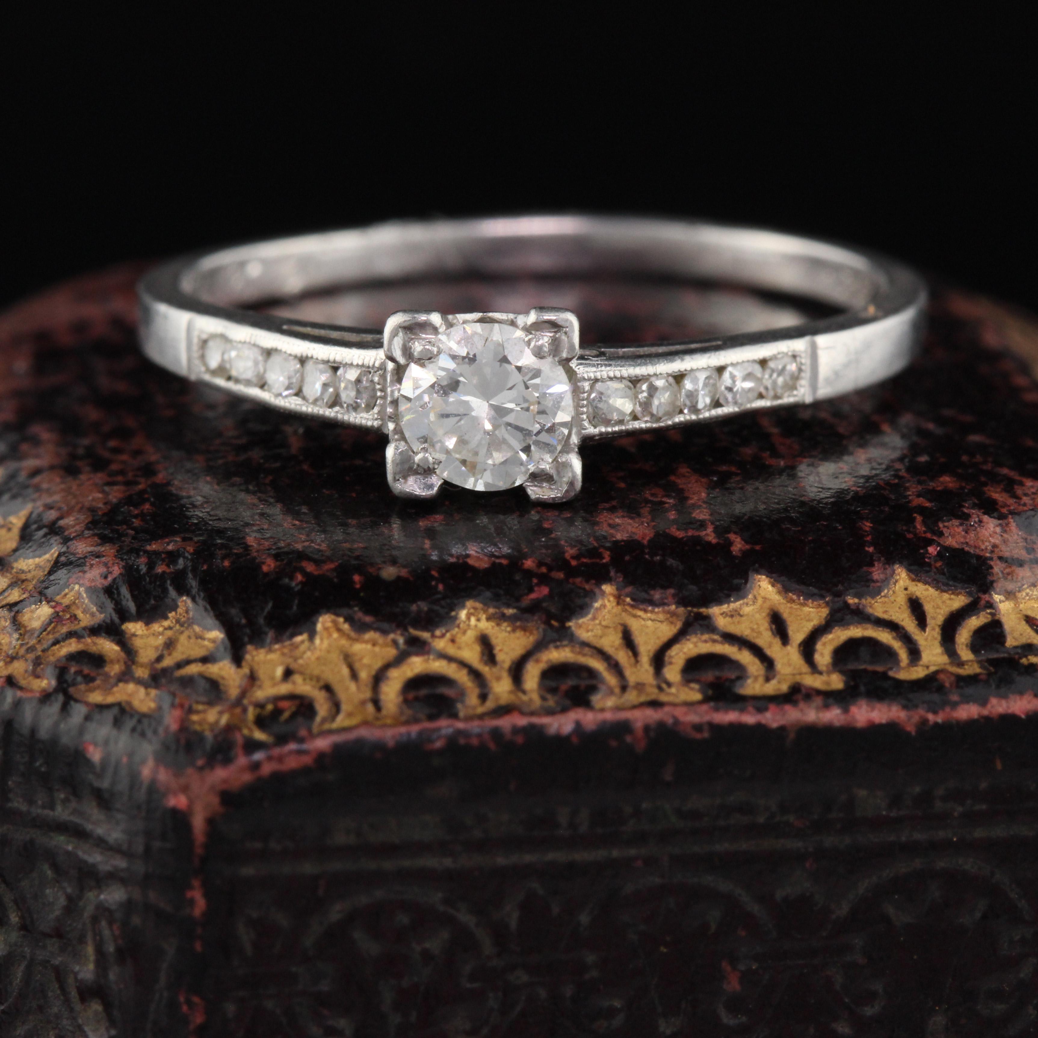 Il s'agit d'une bague de fiançailles éternellement classique des années 1930 en platine avec un diamant rond au centre et cinq petits diamants ronds de chaque côté. L'intérieur de la tige est gravé mais a été décoloré. Des parties de la gravure sont