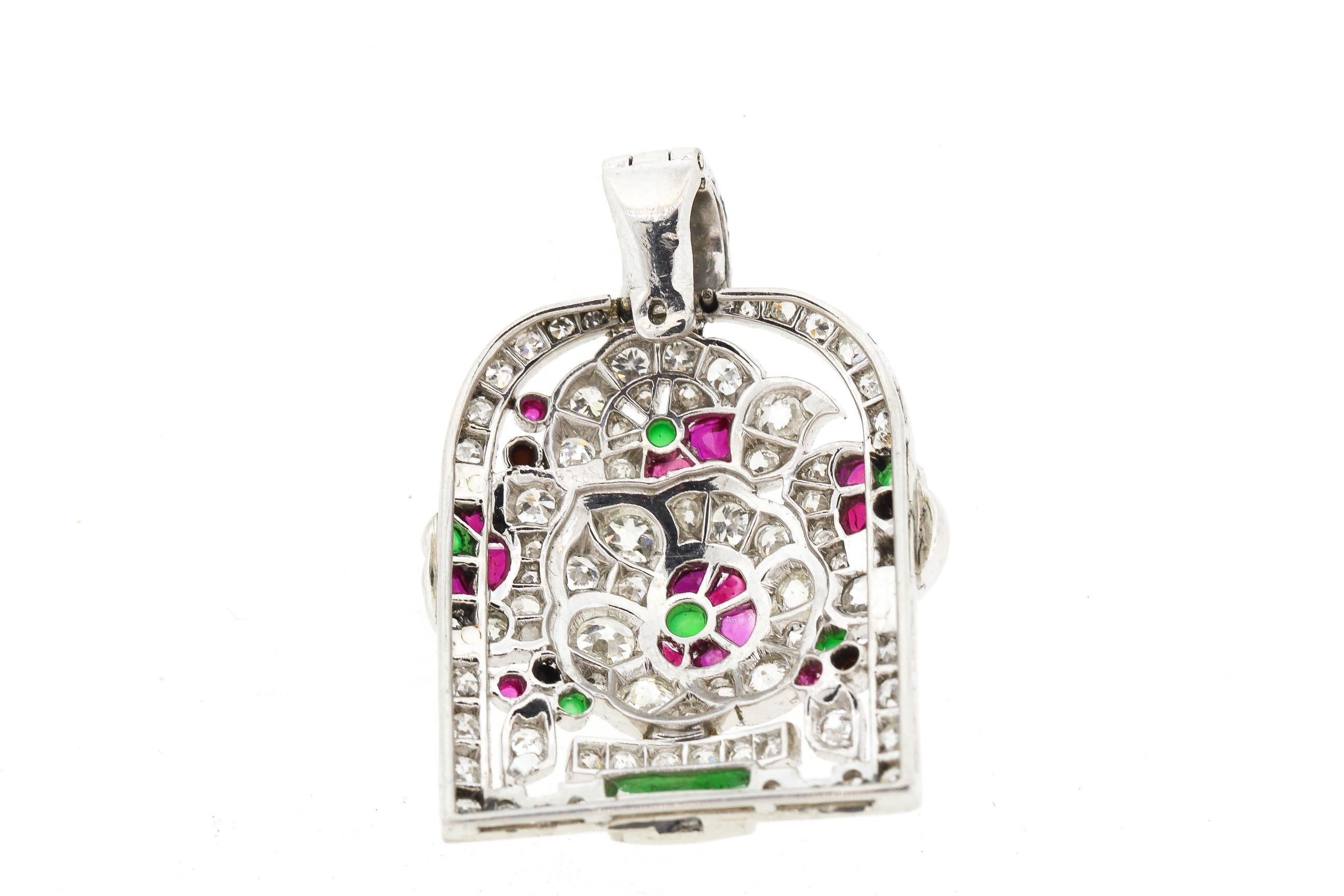 An antique Art Deco diamond and gem set jardiniere pendant made in platinum circa 1920. This pendant is a colorful rendering of a potted flower set with buff top rubies, chrysoprase and onyx. The pendant is dimensional and bright. The bail opens up
