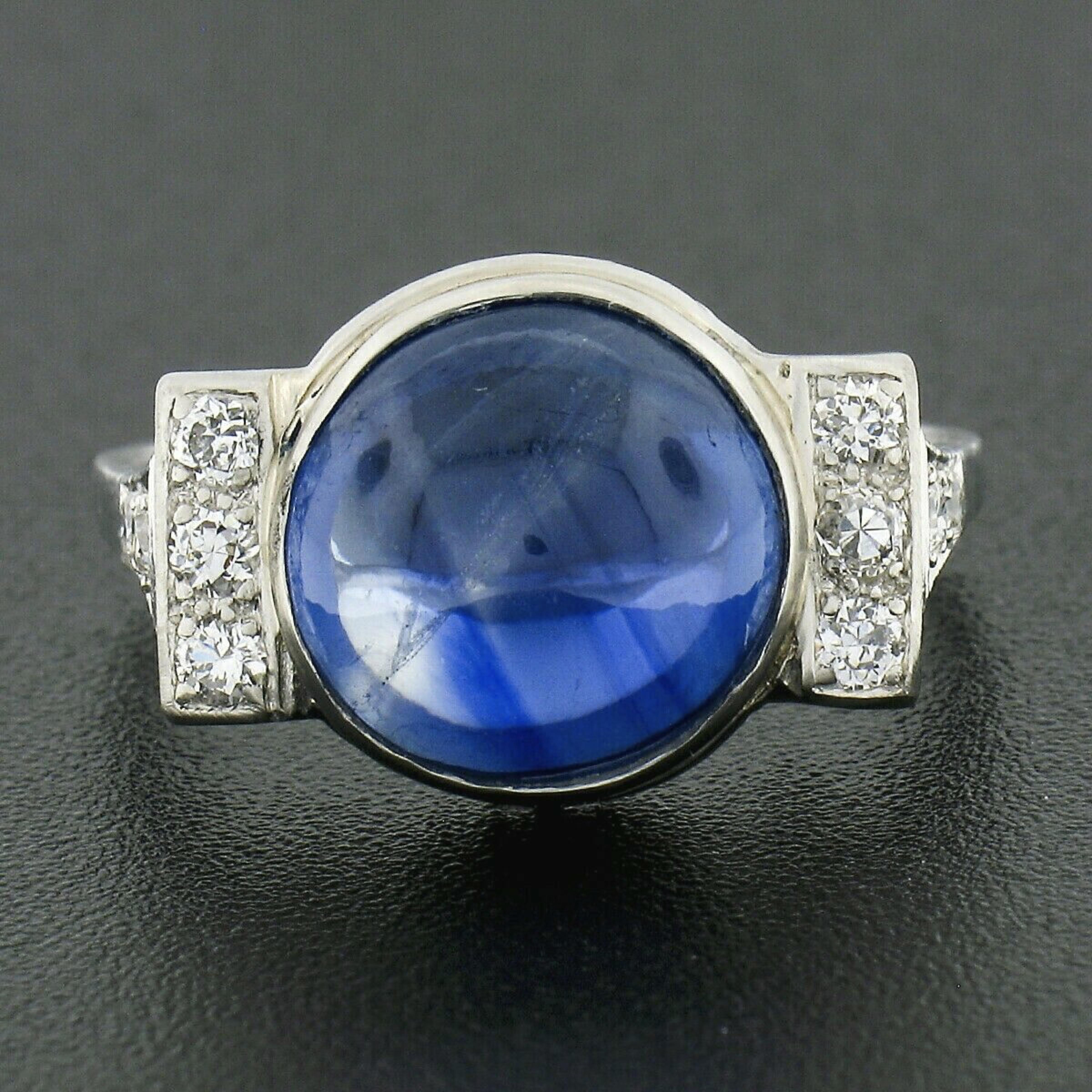 This magnificent antique cocktail ring was crafted during the art deco period from solid platinum and features a gorgeous, Gubelin certified, natural sapphire neatly bezel set at its center. The sapphire is certified as weighing exactly 7.91 carats