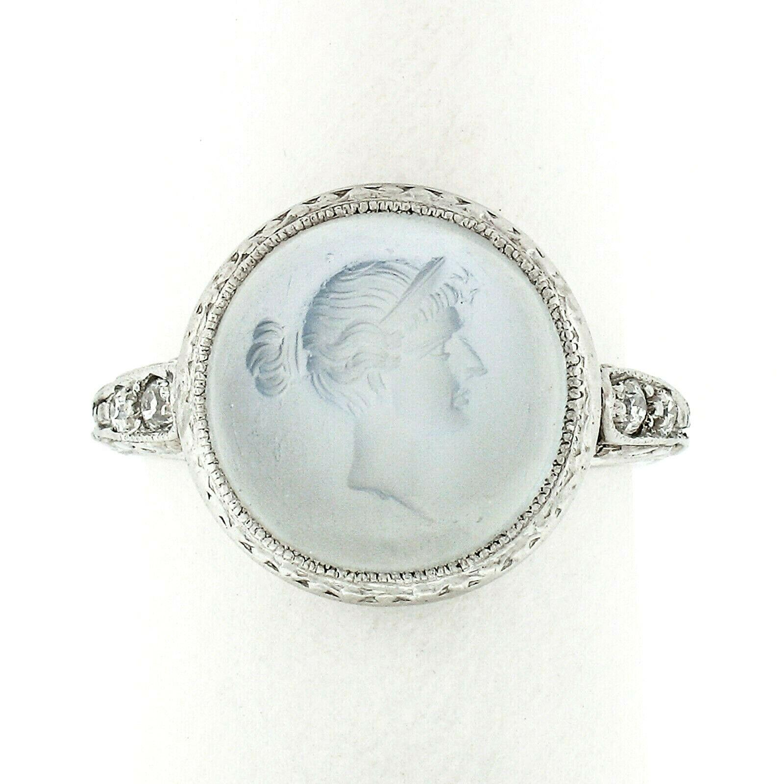 This magnificent antique cocktail ring was crafted from solid 900 platinum during the art deco period and features a carved moonstone intaglio solitaire at its center. The stone displays a very fine translucent blue color which is bezel set and