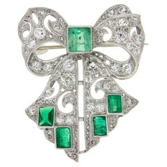 Antiguo broche Art Decó de diamantes talla antigua en platino y esmeralda con gran lazo