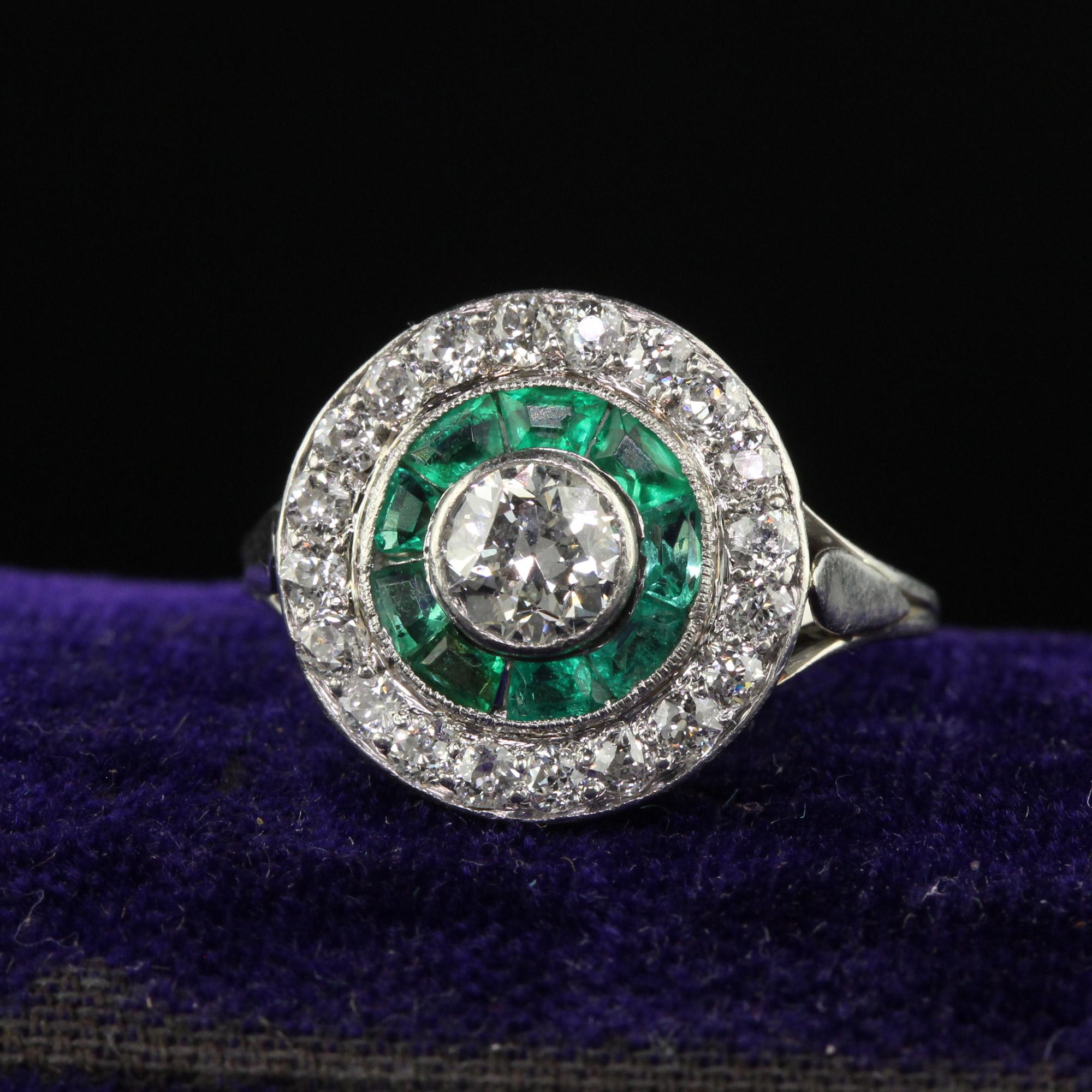 Beautiful Antique Art Deco Platinum Old Euro Diamond and Emerald Engagement Ring. The center holds a beautiful old European cut diamond that is surrounded by natural emeralds. The outer halo has old European cut diamonds as well and the ring is in