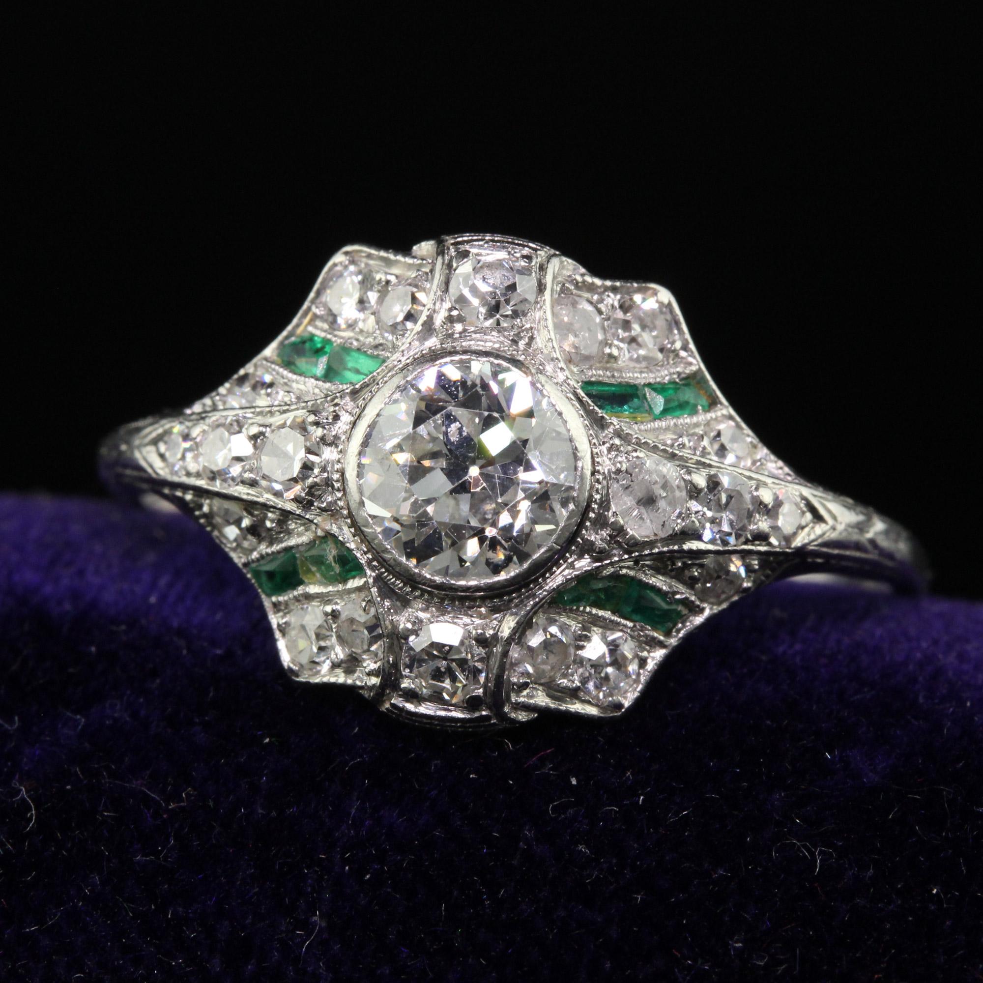 Beautiful Antique Art Deco Platinum Old European Diamond and Emerald Engagement Ring. This incredible engagement ring is crafted in platinum. The center holds a beautiful old European cut diamond that has smaller old European cut diamonds and French