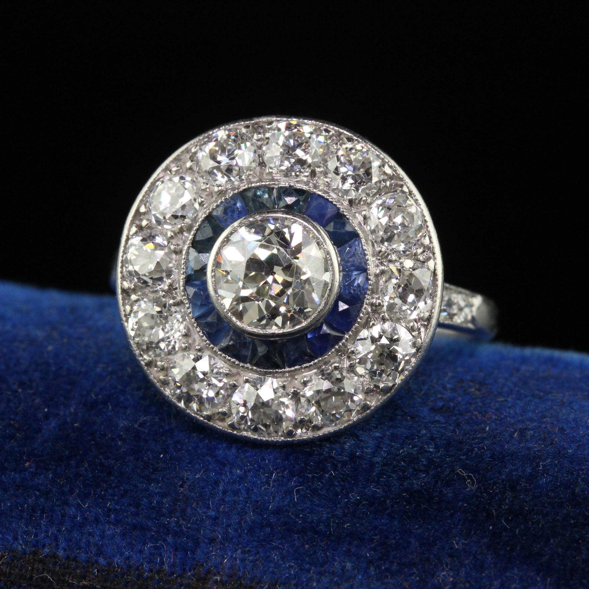Beautiful Antique Art Deco Platinum Old European Diamond and Sapphire Target Engagement Ring. This incredible engagement ring is crafted in platinum. The center holds a gorgeous white and clean old European cut diamond and is surrounded by a row of