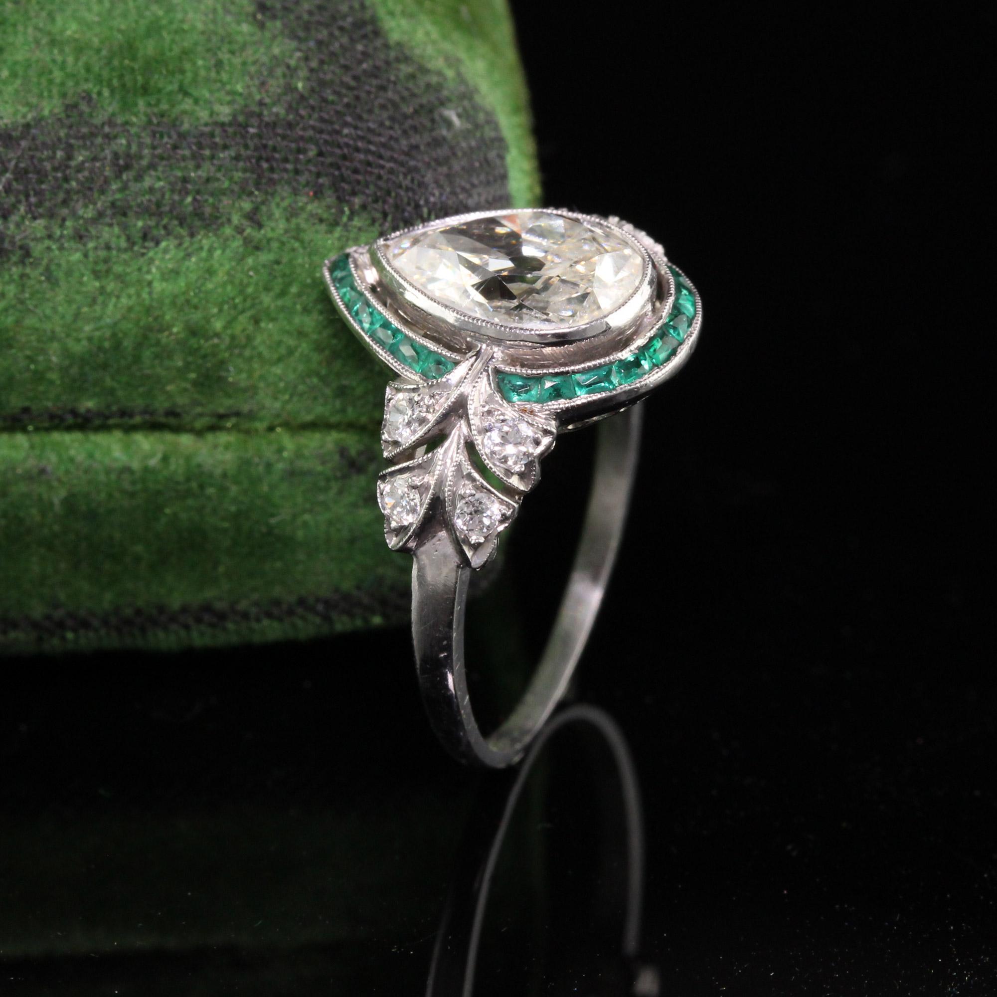 Beautiful Antique Art Deco Platinum Old Pear Shape Diamond Emerald Halo Engagement Ring. This unbelievable engagement ring features an old pear shape diamond in the center surrounded by emeralds and delicate flower sides. The center is approximately