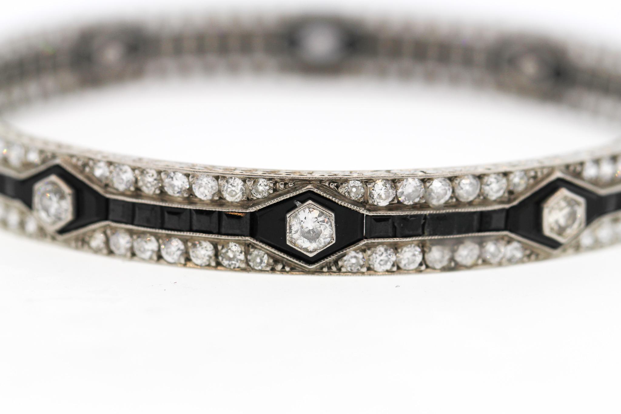 A spectacular Art Deco platinum onyx and diamond bangle bracelet, circa 1920. This bracelet has a strong geometric pattern created by the calibre cut onyx. It is set with Old European Cut diamonds, 150 stones weighing approximately 12.50 carats. The