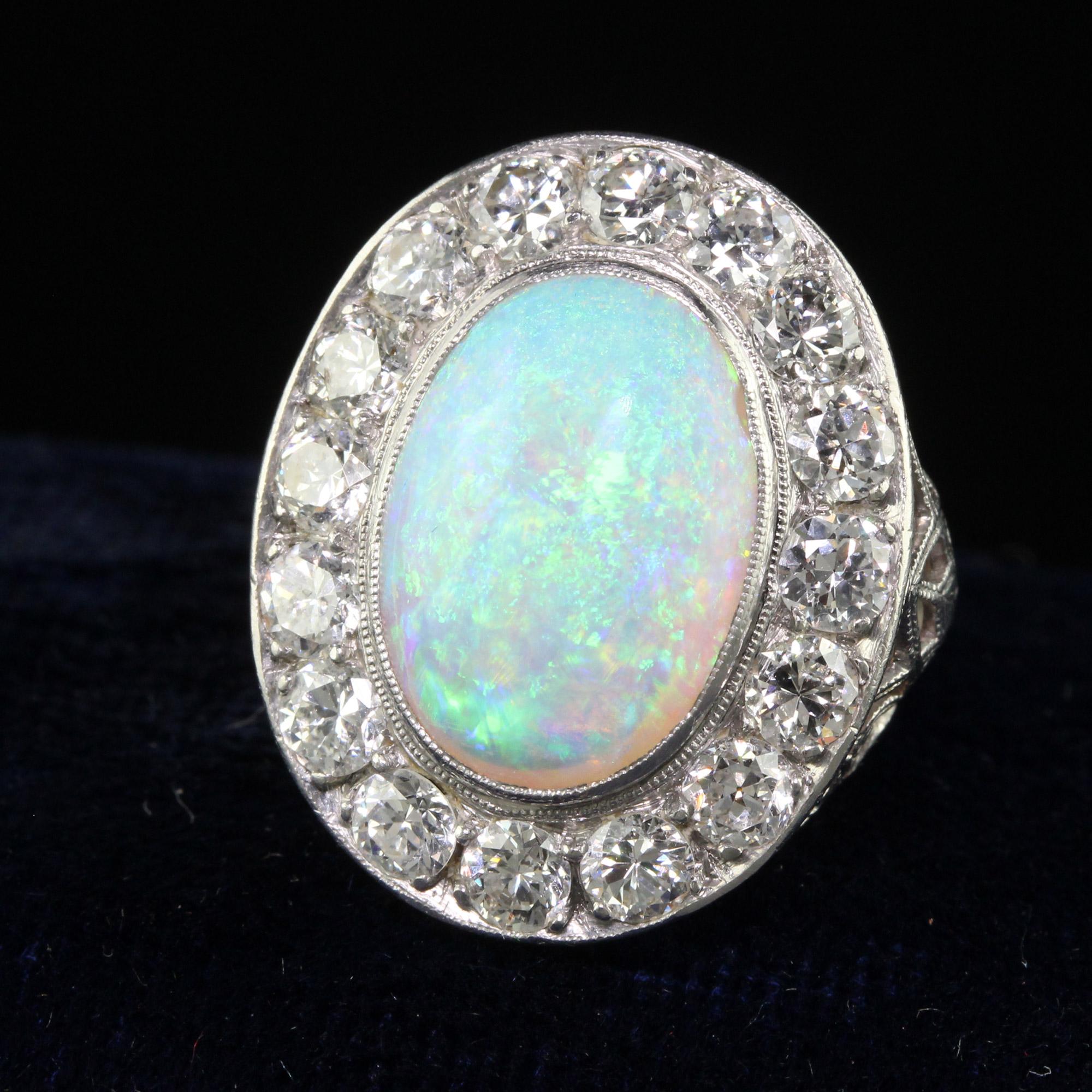 Beautiful Antique Art Deco Platinum Opal and Old Euro Diamond Halo Ring. This gorgeous art deco cocktail ring is crafted in platinum. The center holds a natural opal with a beautiful play of color. The center opal is surrounded by white old European