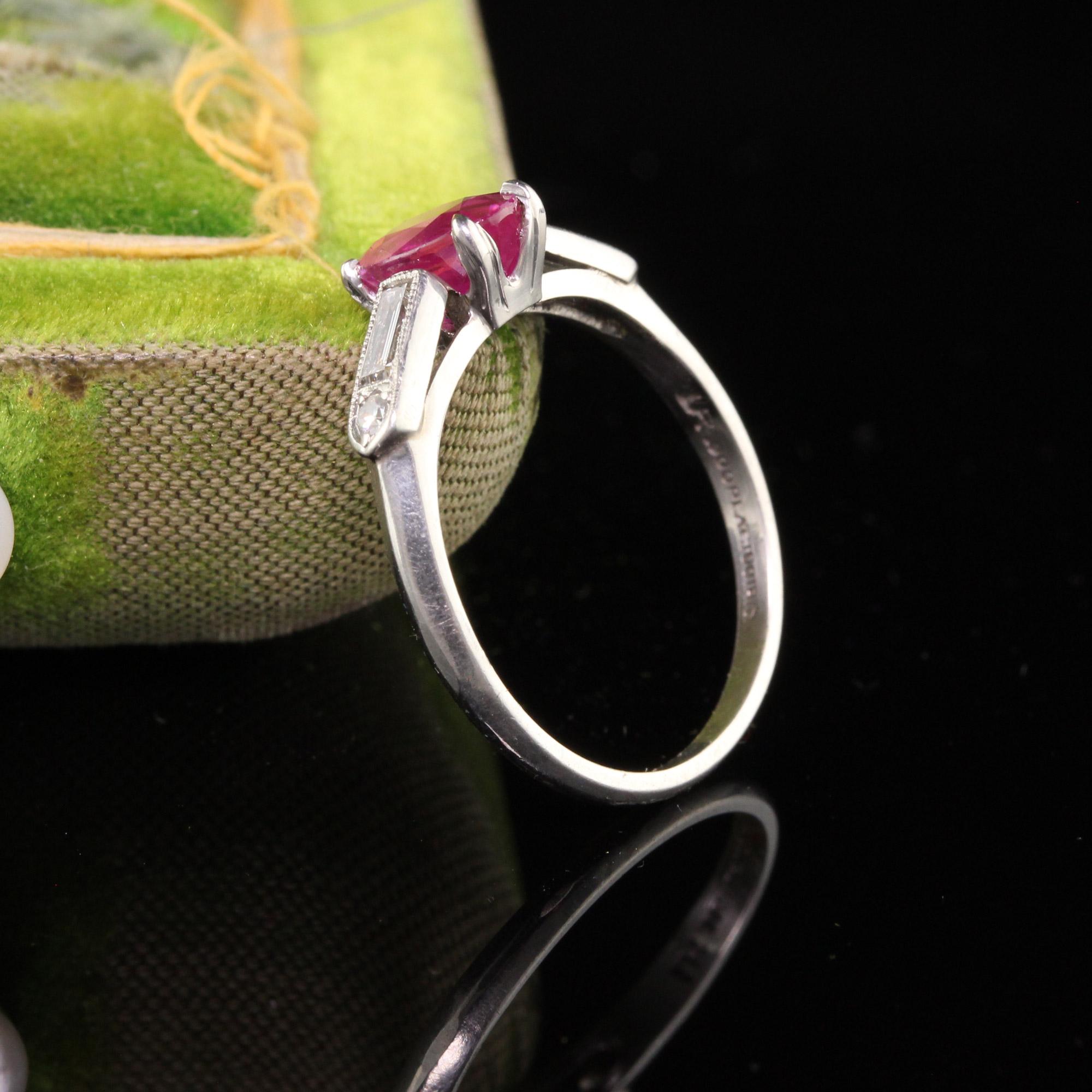Ein wunderschöner antiker Art Deco Verlobungsring aus Platin mit Rubinen und Diamanten. Dieser schöne Ring zeigt einen oval geschliffenen Rubin, der zwischen einer heißen rosa und roten Farbe liegt. Er hat Baguette-Diamanten und einen einzelnen