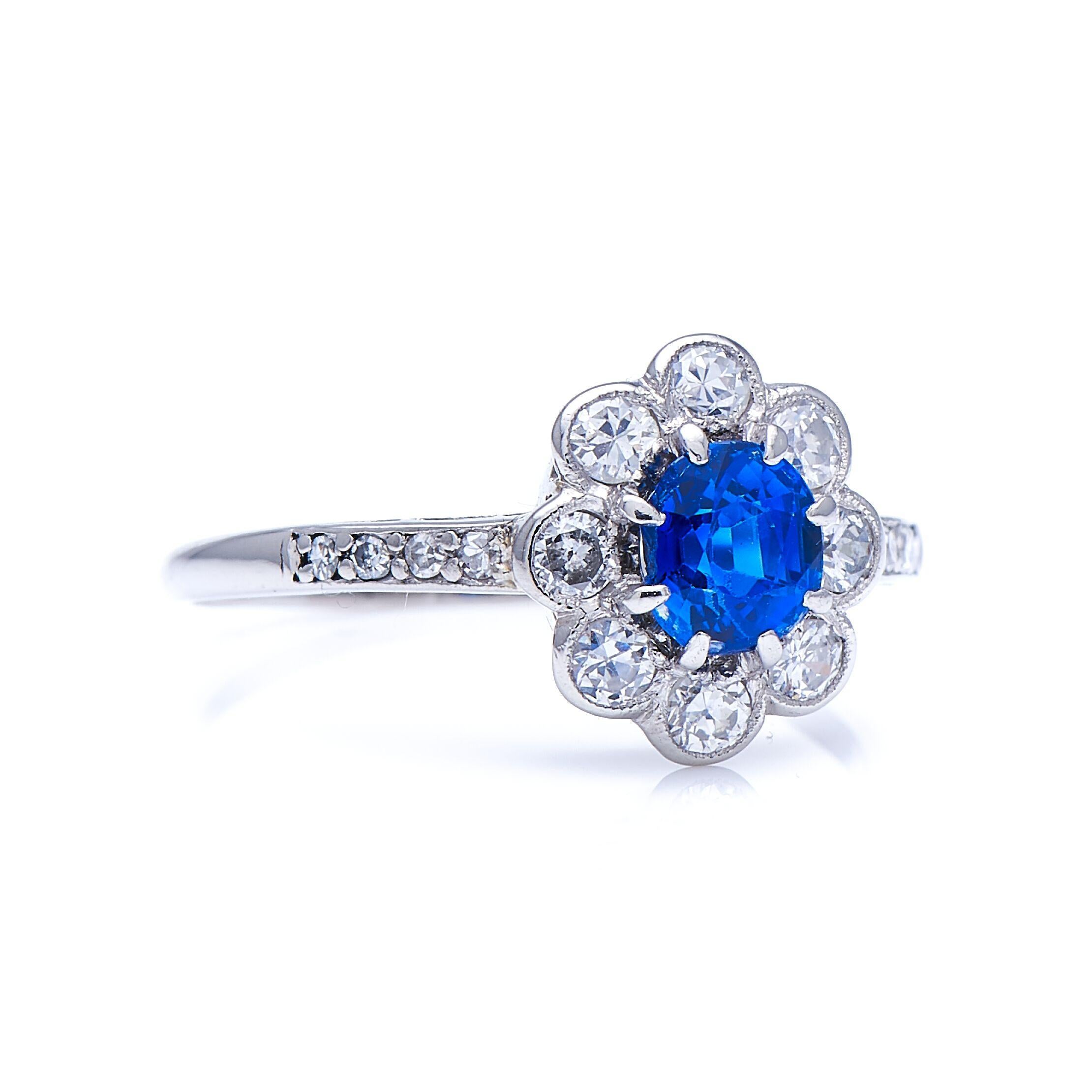 Sapphire and diamond ring, 1920s. A delicate, floral sapphire and diamond cluster, this ring is claw-set with a deep, rich blue sapphire, surrounded by a floral arrangement of circular-cut diamonds, leading down into single-cut diamond shoulders.