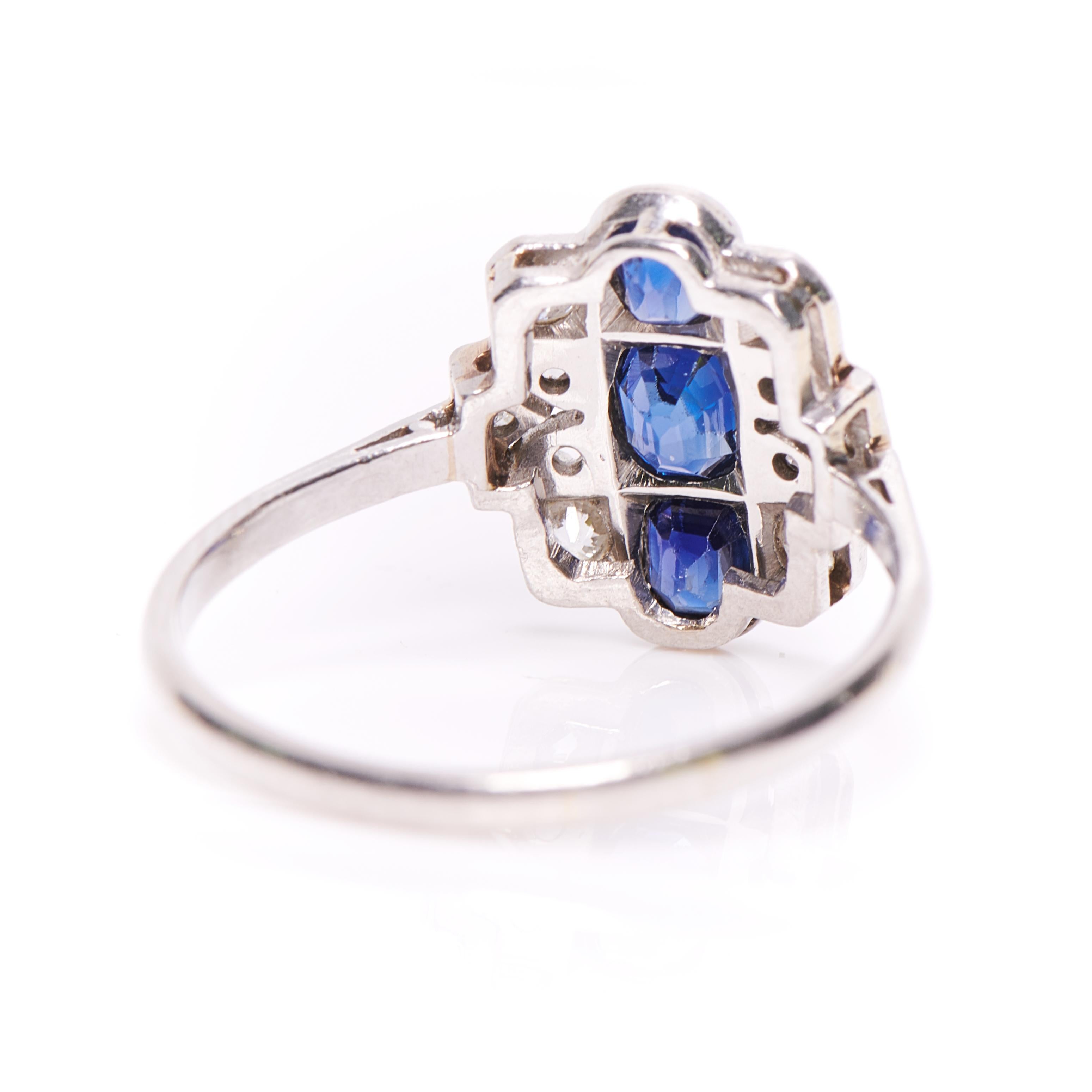 Art Deco sapphire and diamond ring, circa 1925. Set with three oval-cut sapphires of exceptional blue colour and clarity in rubover settings. Further set with old cut diamonds interspersed with a subtle but sinuous openwork design to form an