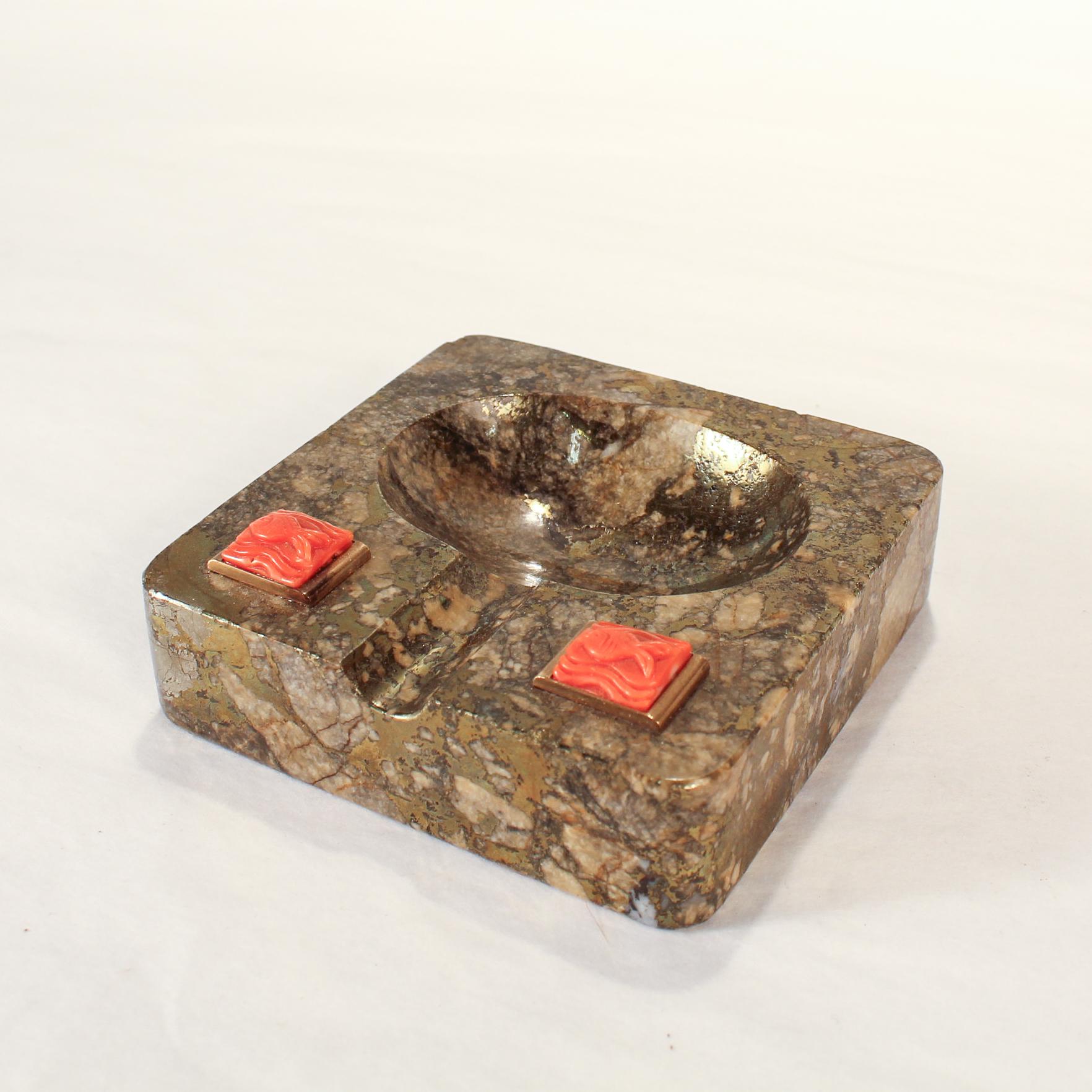 A fine antique Art Deco pyrite hardstone & coral ashtray.

With two coral plaques each having a carved fish. 

This piece feels as if it belongs in 1930's Havana or Miami.

Simply an amazing Art Deco artifact! 

Date:
Early 20th