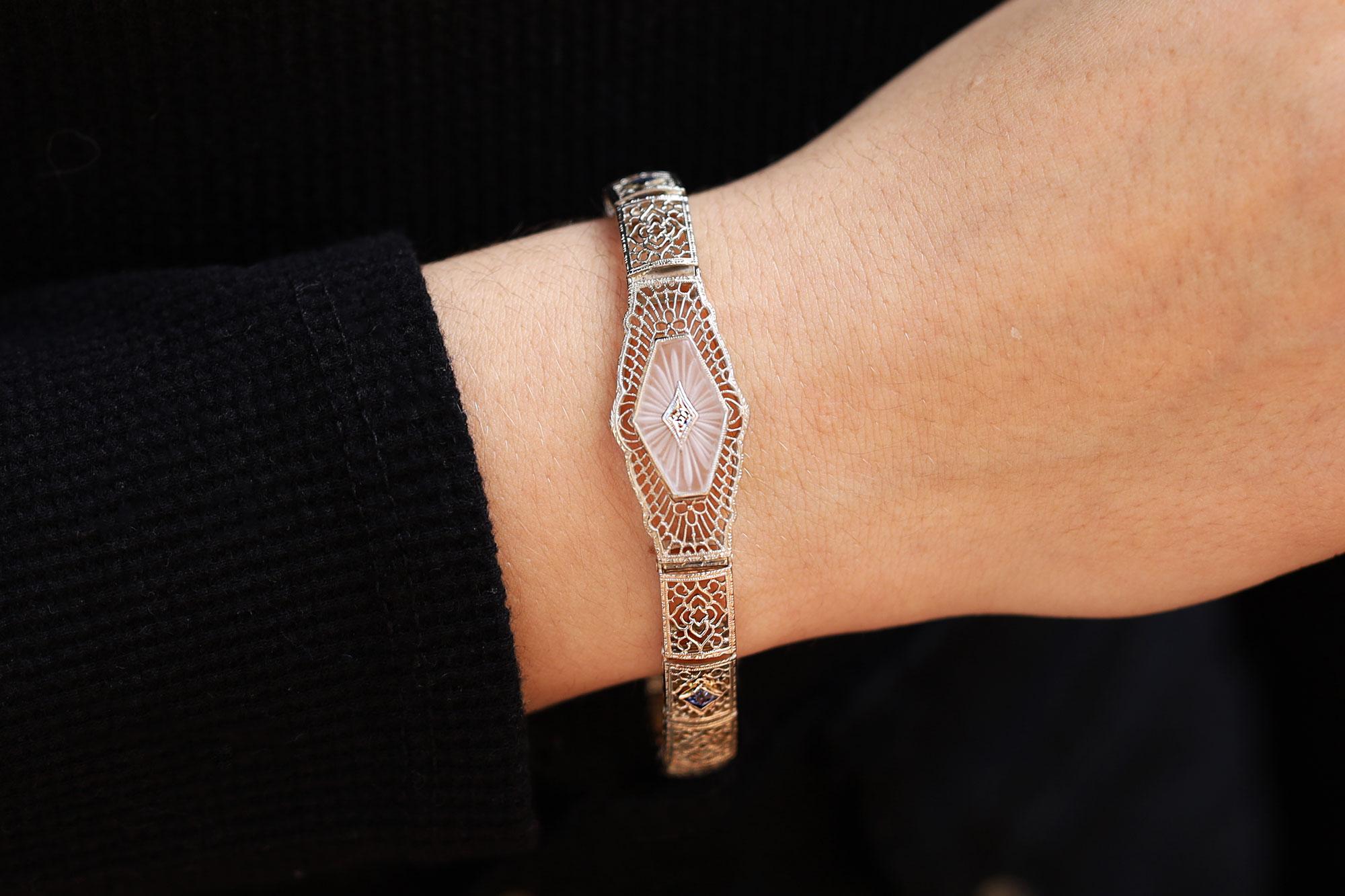 A fabulous filigree bracelet centered by a carved, sun-ray rock crystal plaque displays all of the charm of its Art Deco vintage. The lacy and airy pierced open-work links are finely fabricated of 14k white gold and drapes luxuriously on your wrist.