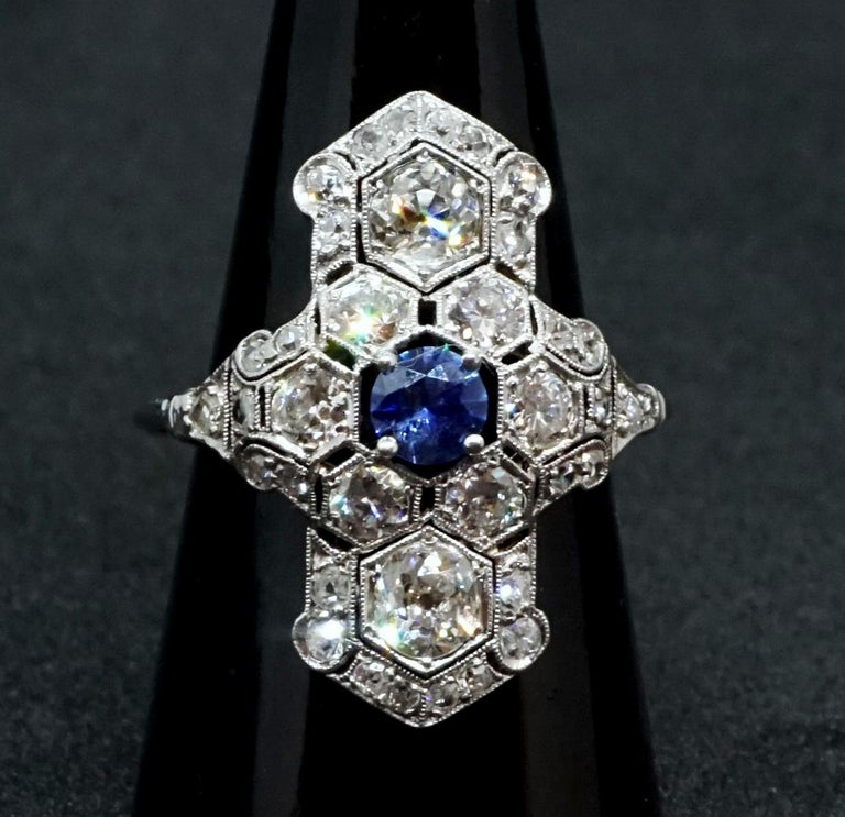 Delicate antique navette-shaped old brilliant-cut diamond ring, with a centered old cut saphire estimated 0.2 carat, surounded by six old brilliant-cut diamonds which are embedded in an openwork honeycomb millegrain edge collet network, which is
