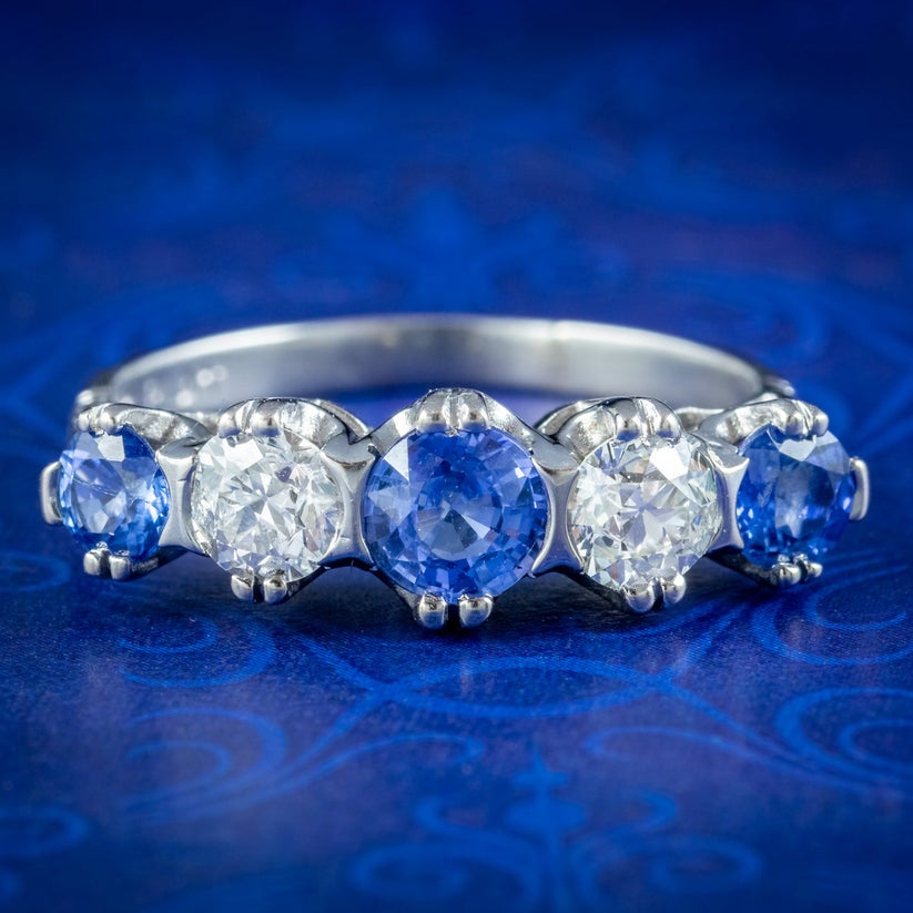 Ein prächtiger antiker Ring mit fünf Steinen aus den frühen 1900er Jahren, geschmückt mit abwechselnd blauen Saphiren und weißen Diamanten im alten europäischen Schliff, die einen schönen Kontrast bilden und sich gegenseitig ergänzen. 

Die Saphire