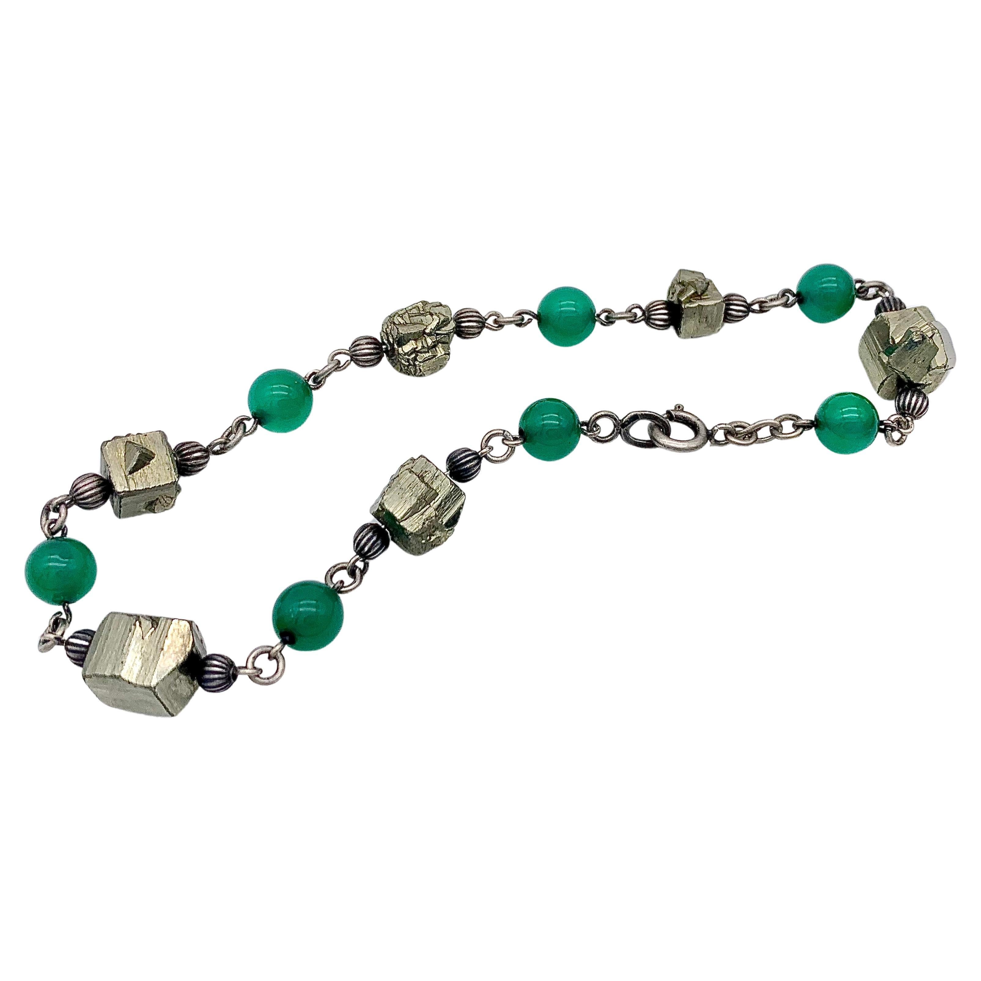 This bracelet was created around 1915-1920 out of silver, grooved silver beads, green chalcedony beads and cubes of pyrite. The chalcedony beads, the silver beads as well as the pyrite cubes have been threaded onto silver wire. The pieces of wire