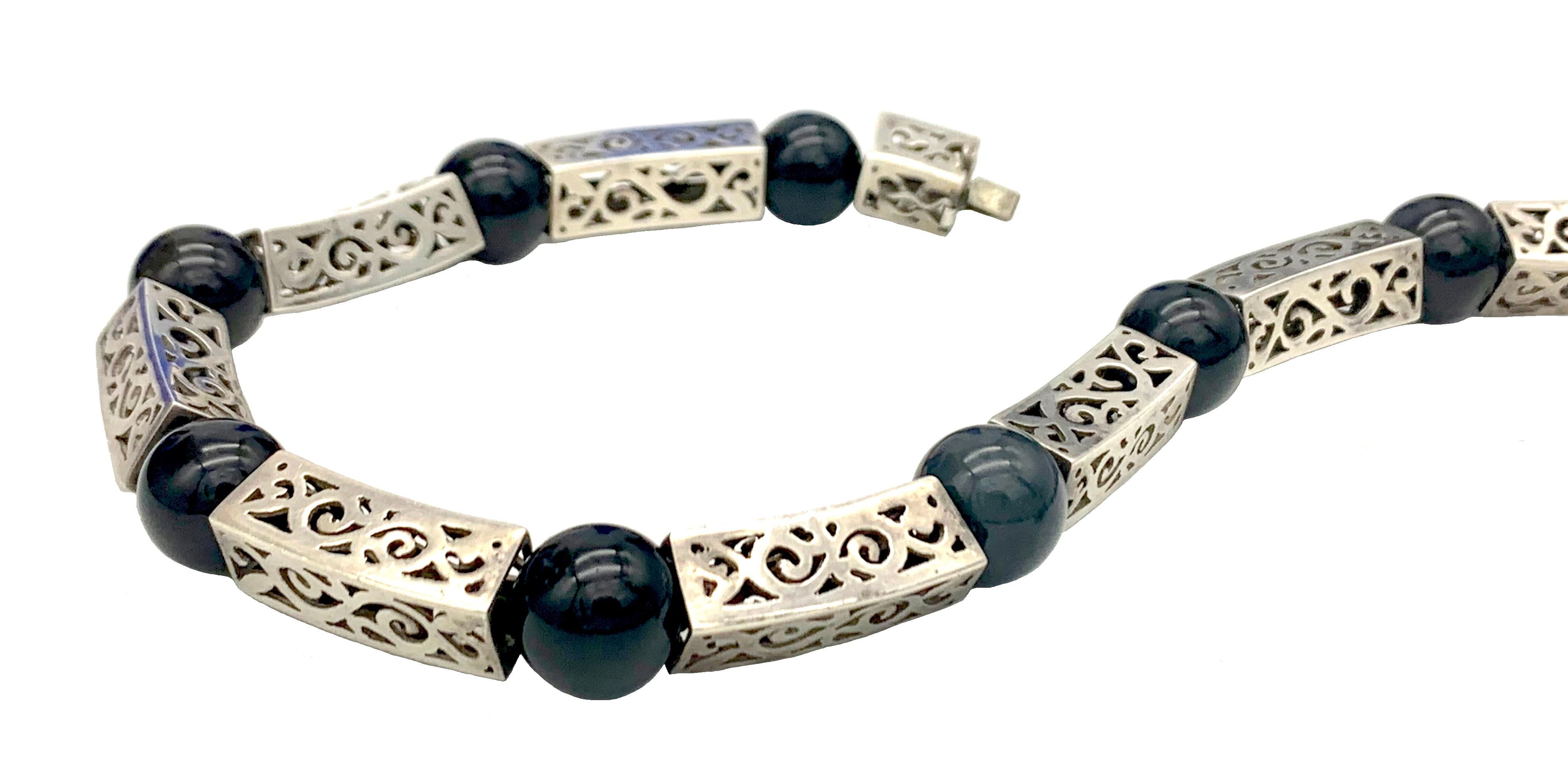 This striking Art Deco link necklace is made out of fourteen cast  silver elements with a cut out decoration. One of the fourteen segments is the clasp which is fitted with two safety  Fourteen onyx beas alternate with the siver elements and are