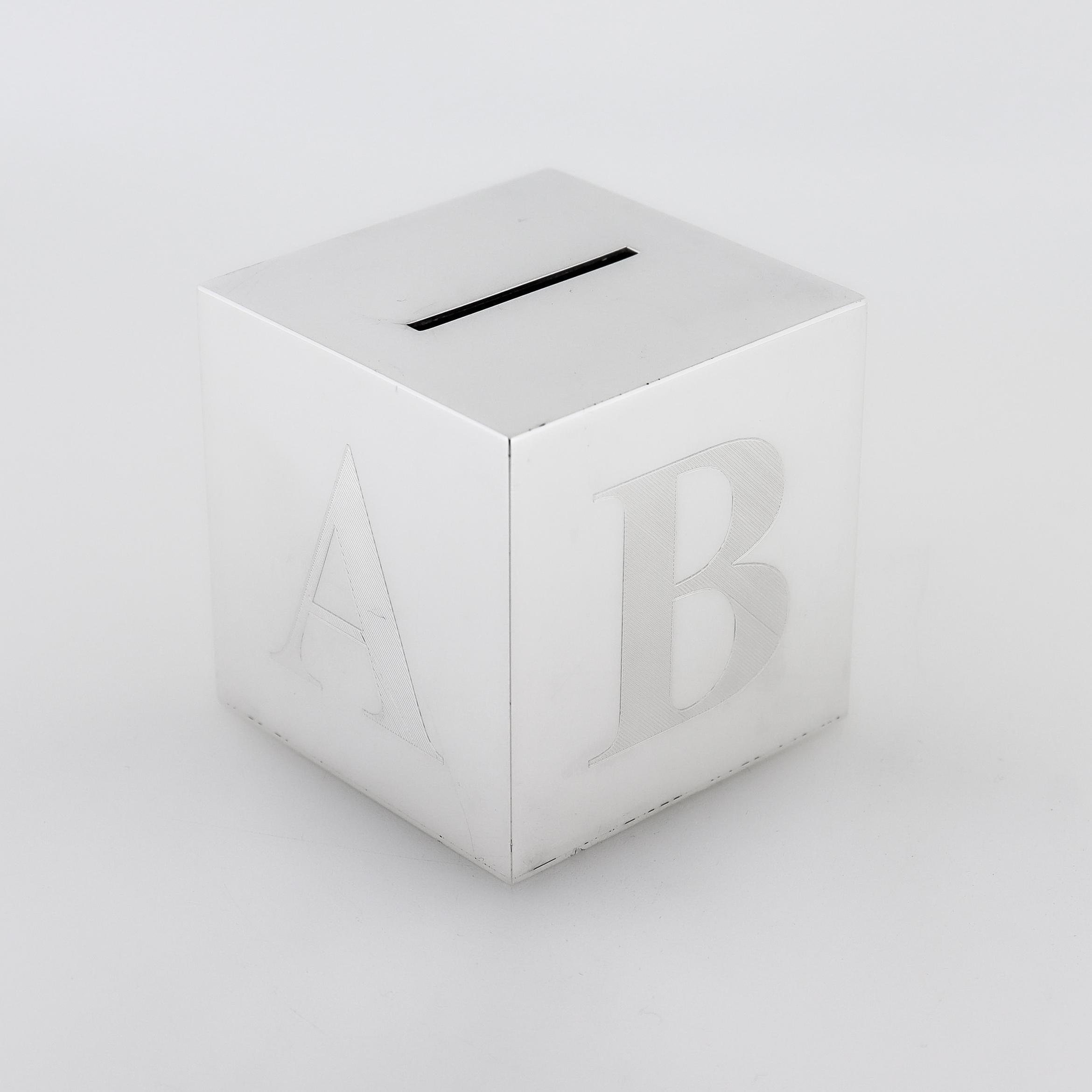 Une belle pièce de monnaie ou tirelire Art Déco.

En argent sterling.

Sous la forme d'un cube épais d'un bloc de jouet en bois ABC.

Gravé sur trois côtés en lettres capitales.

La partie supérieure est munie d'une large fente pour les pièces (ou