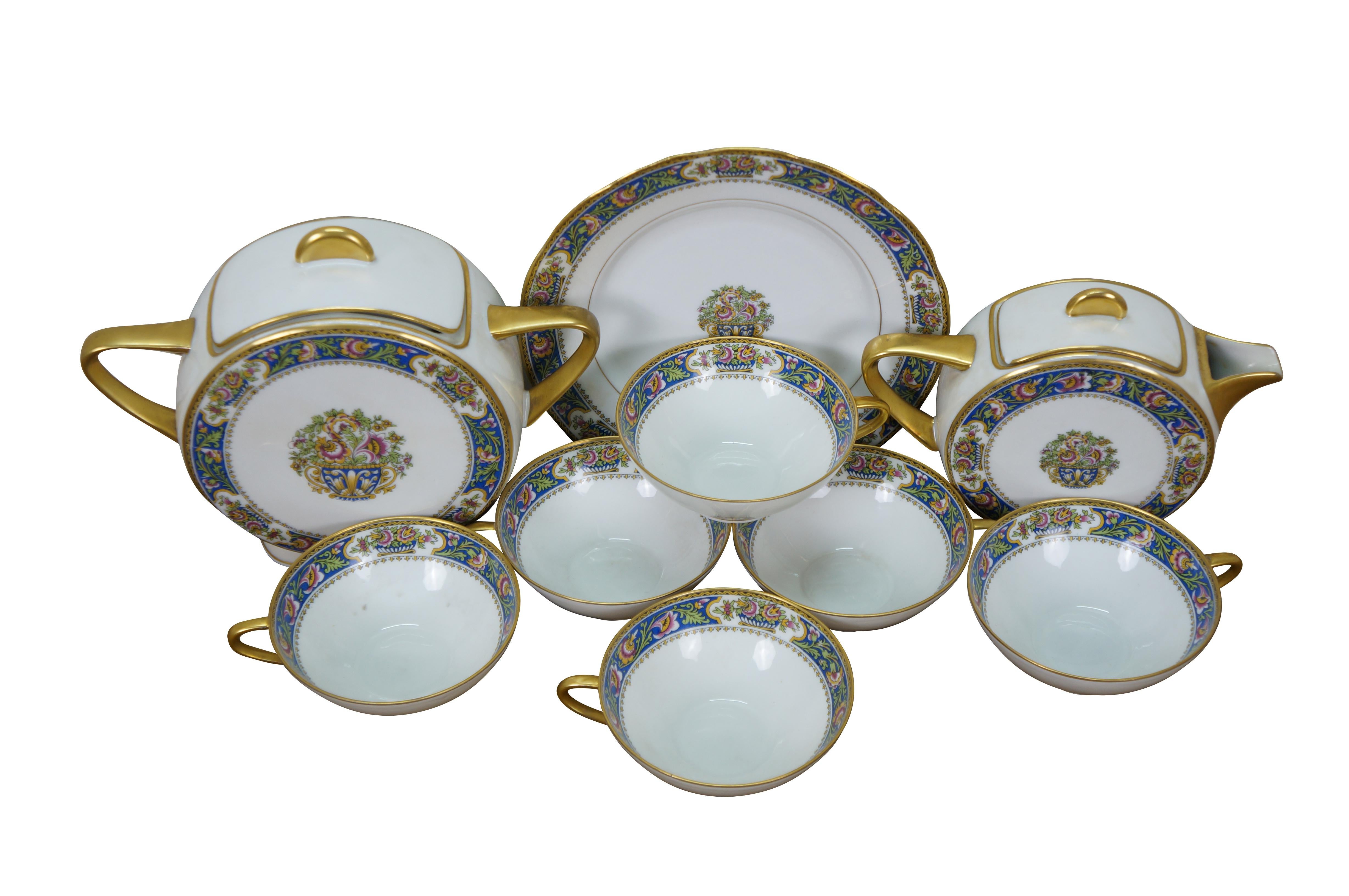 11 piece antique French Limoges porcelain demitasse tea set by TLB (Touze, Lemaître Frères & Blancher). Pots feature a stylized round, art deco inspired shape. White porcelain with gold gilt details and folk art style floral pattern in blue, pink,