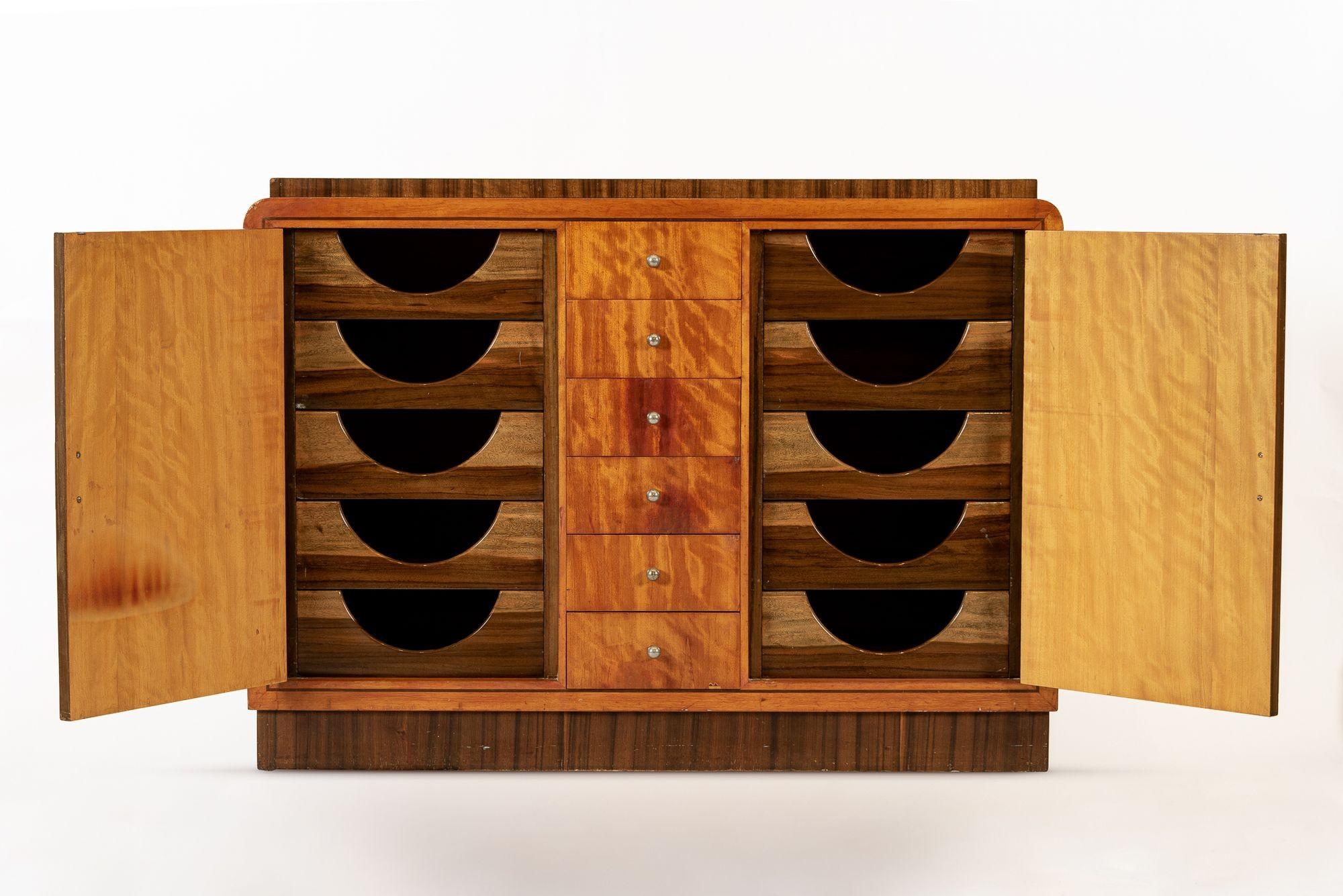 This antique Art Deco lacquered wood dresser cabinet is circa 1930 and is part of a matching set that includes a tall nighstand cabinet. This handcrafted, two-toned wooden dresser has a distinctive design with six small dovetailed drawers at center